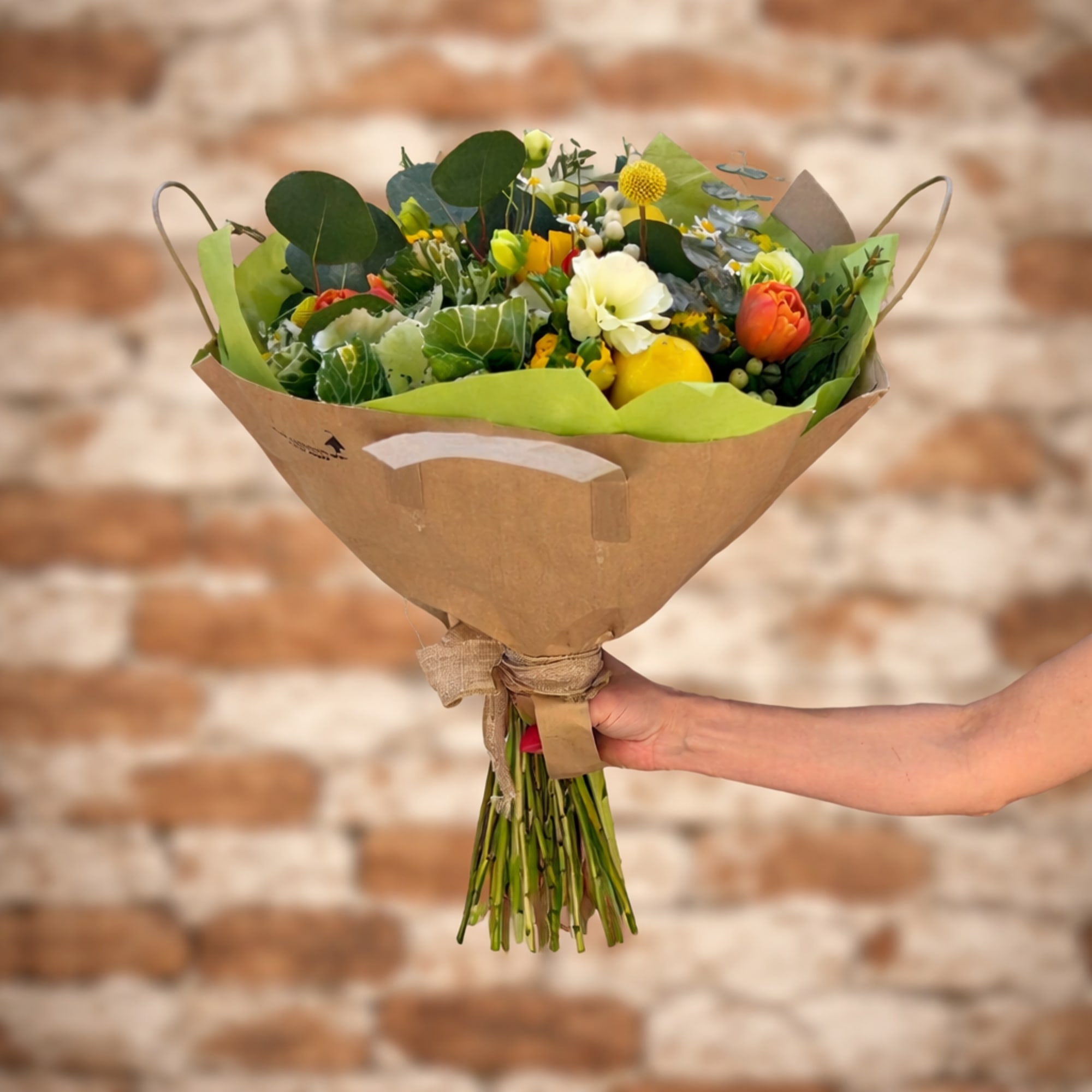 Hand-tied bouquet in bright yellow hues with fresh lemons, butterfly ranunculus, and