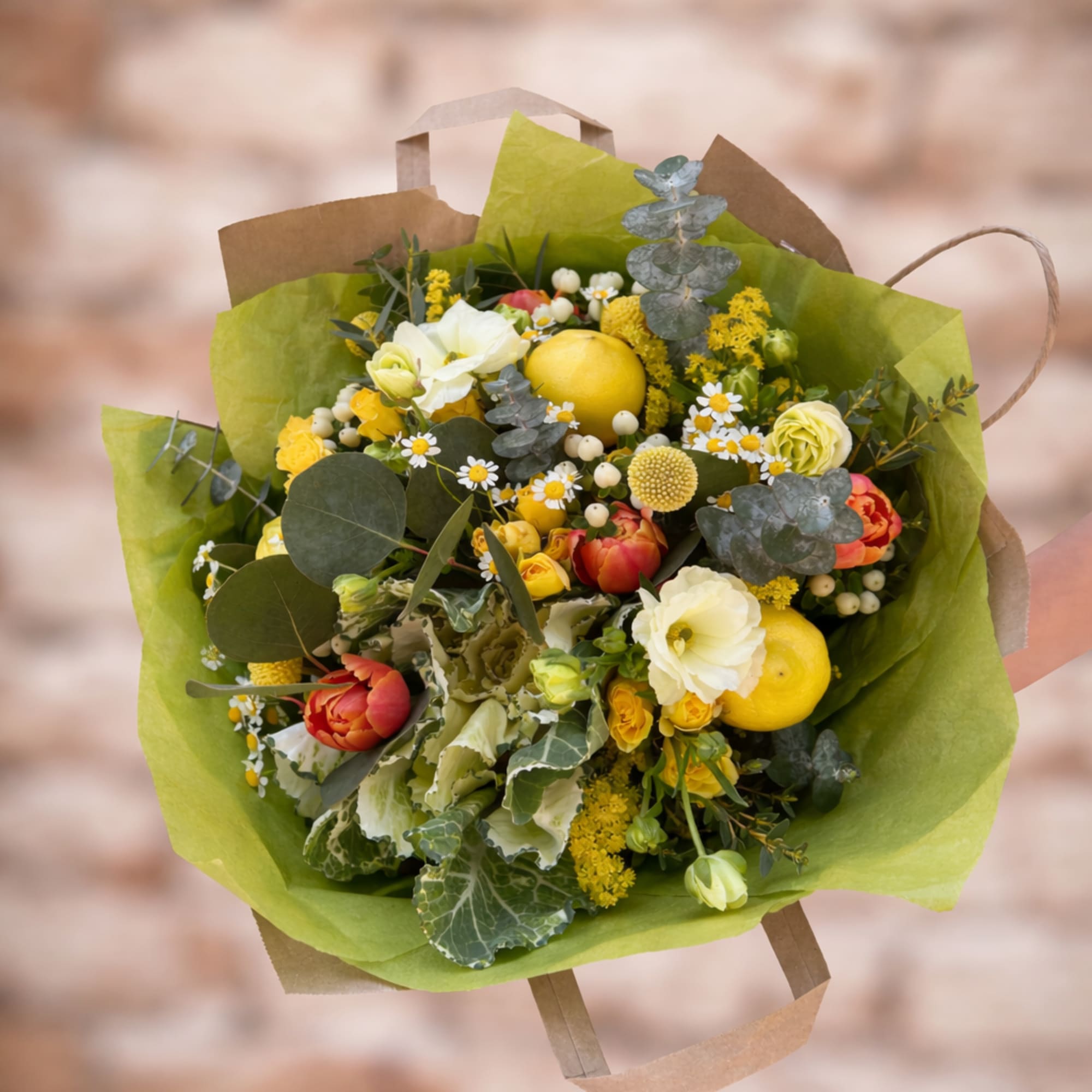 Hand-tied bouquet in bright yellow hues with fresh lemons, butterfly ranunculus, and