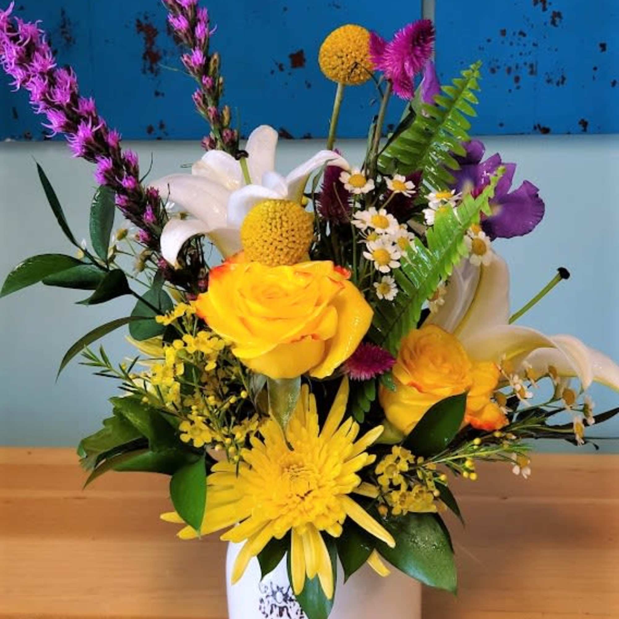 Mixed flowers, Yellow roses, and Purple Sage in a colorful vase. Due