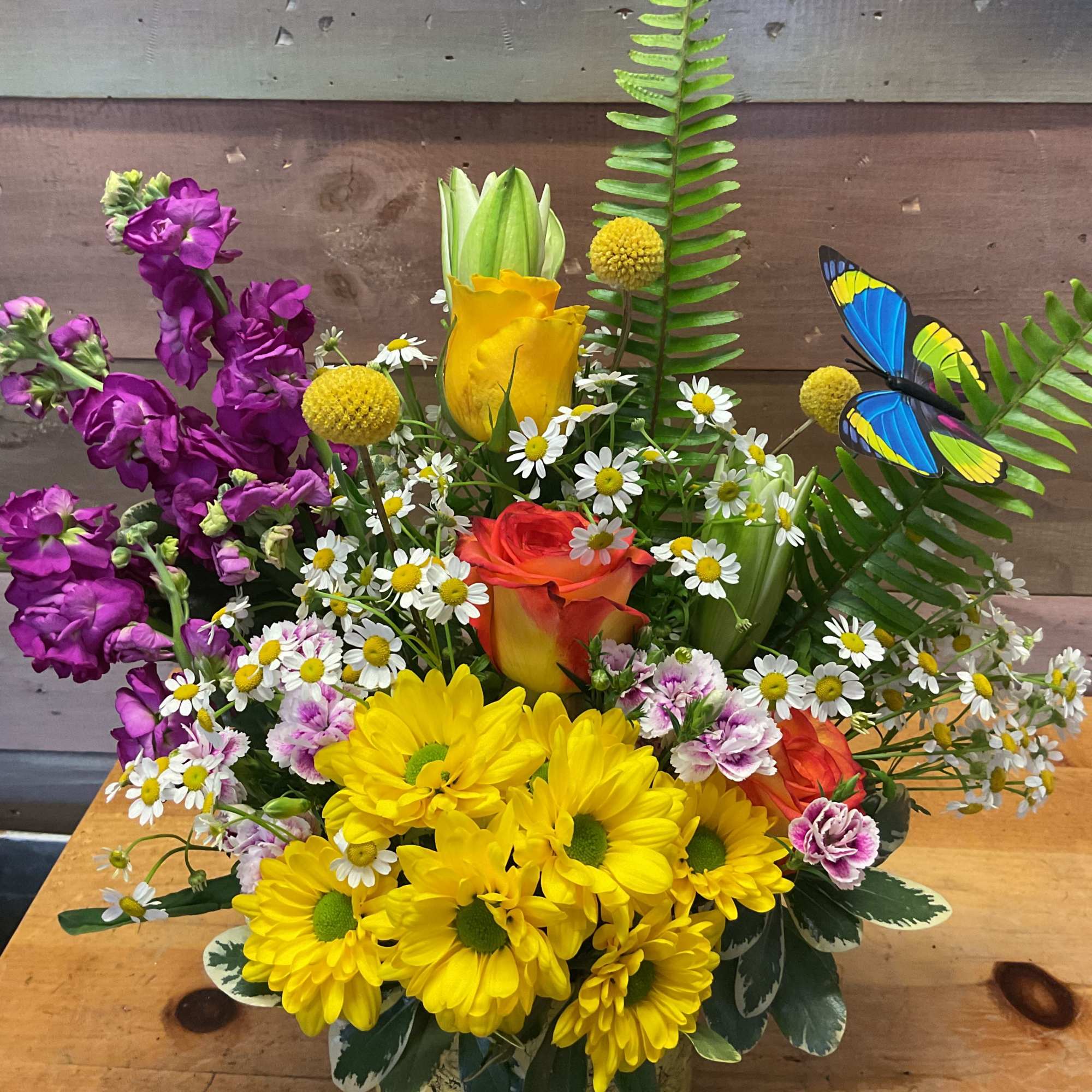 Mixed flowers, Yellow roses, and Purple Sage in a colorful vase. Due