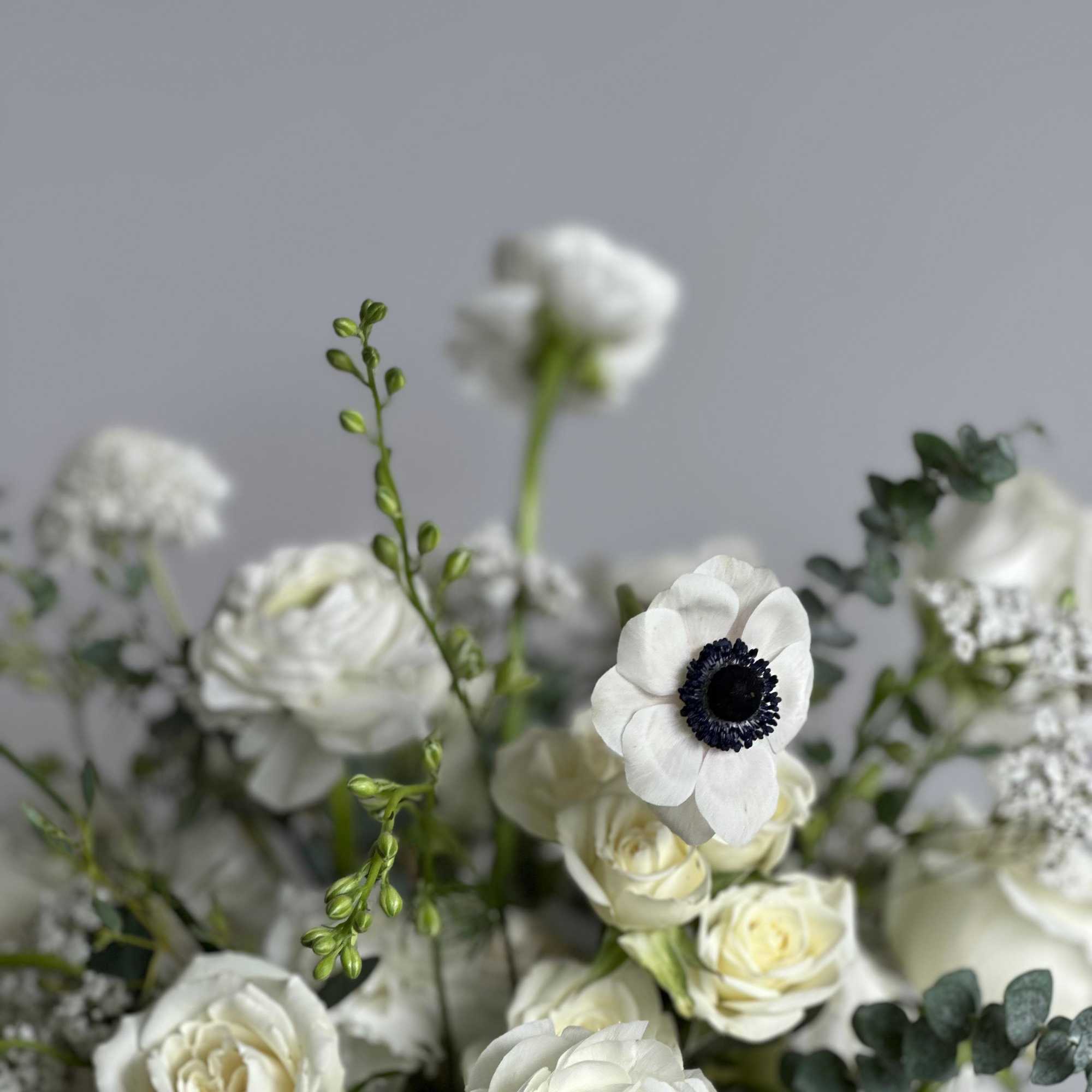 A white low vase filled with elegant all-white flowers. 

Flower types may