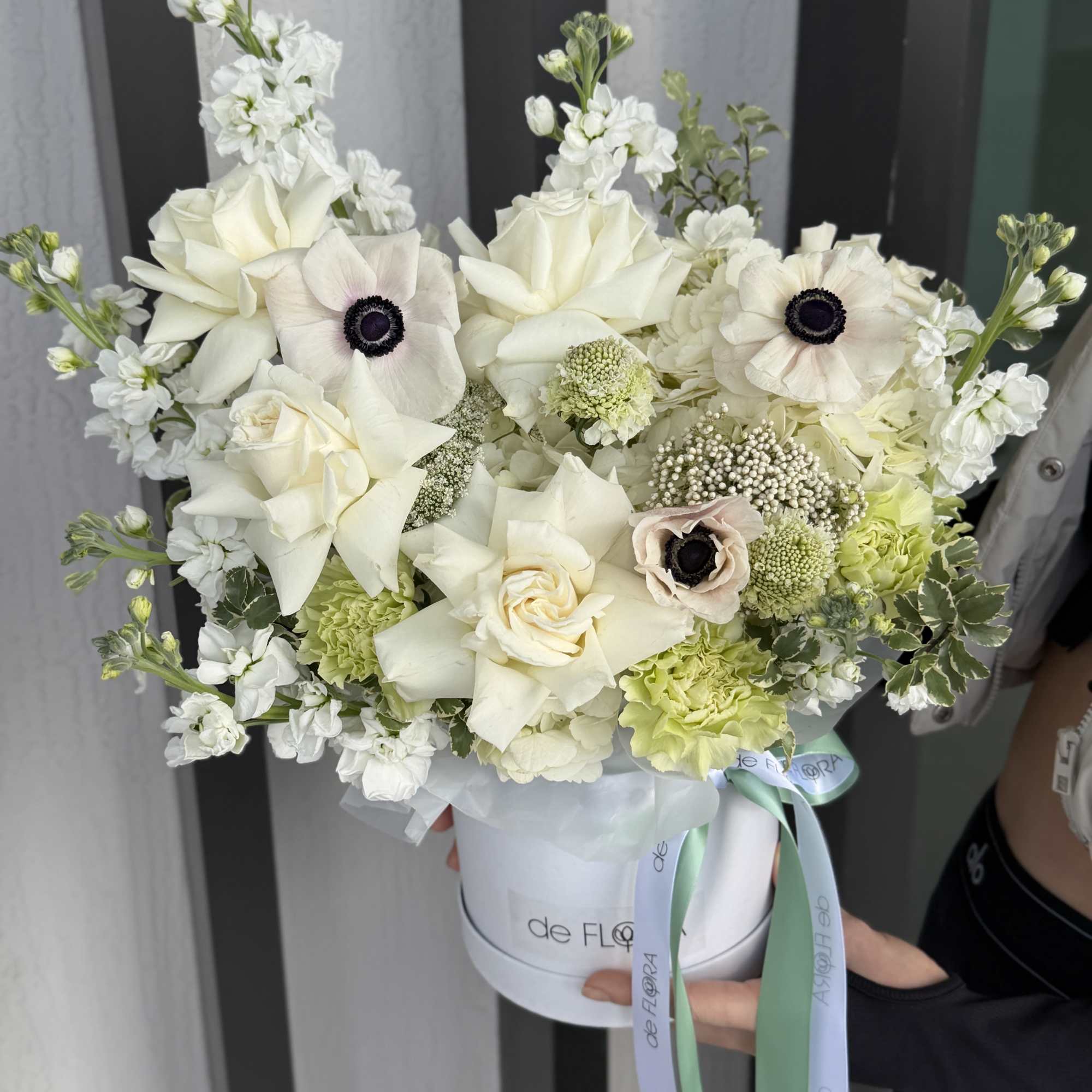 An exquisite arrangement of creamy white roses, delicate anemones with deep contrasting
