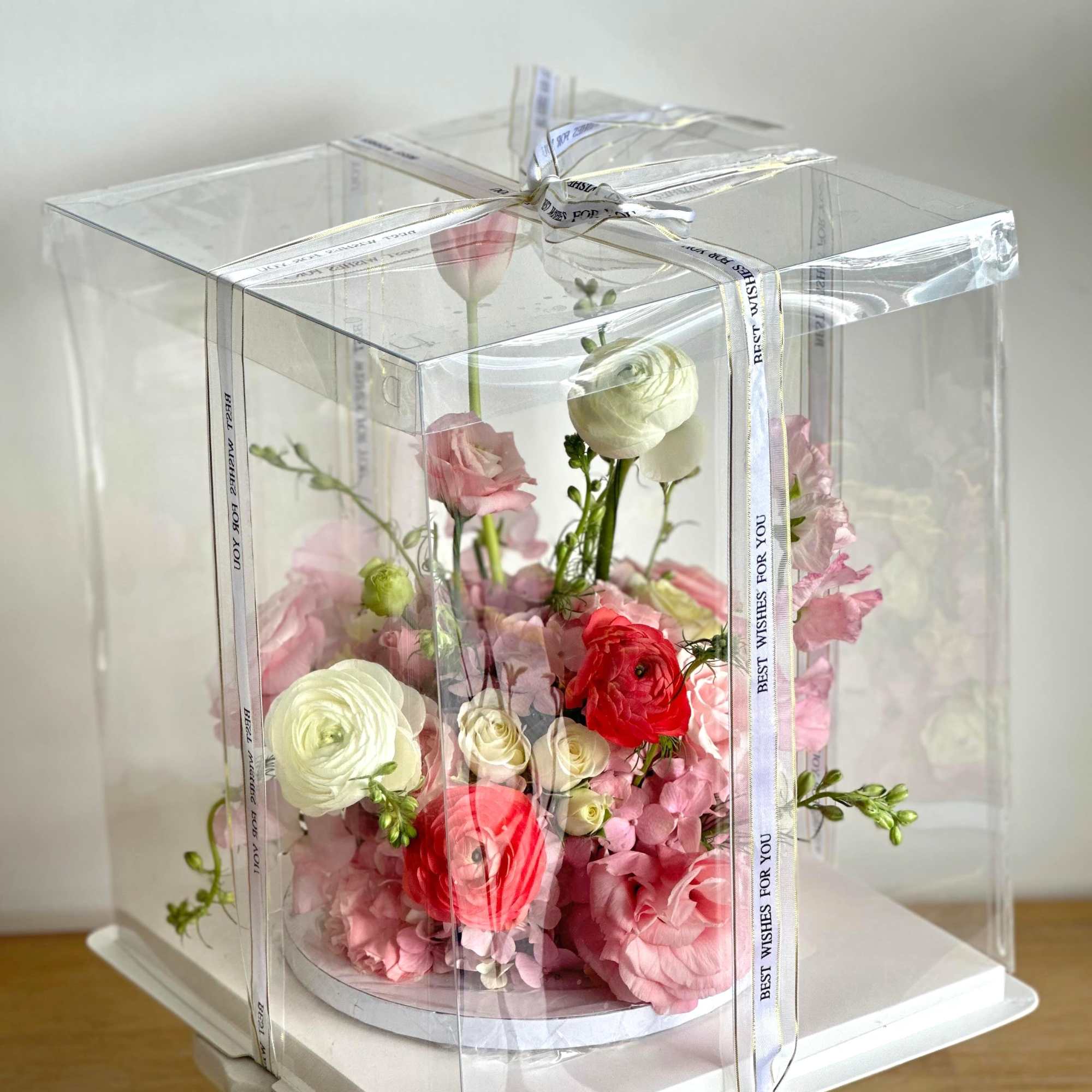 A flower arrangement in the shape of a cake, with pink, light