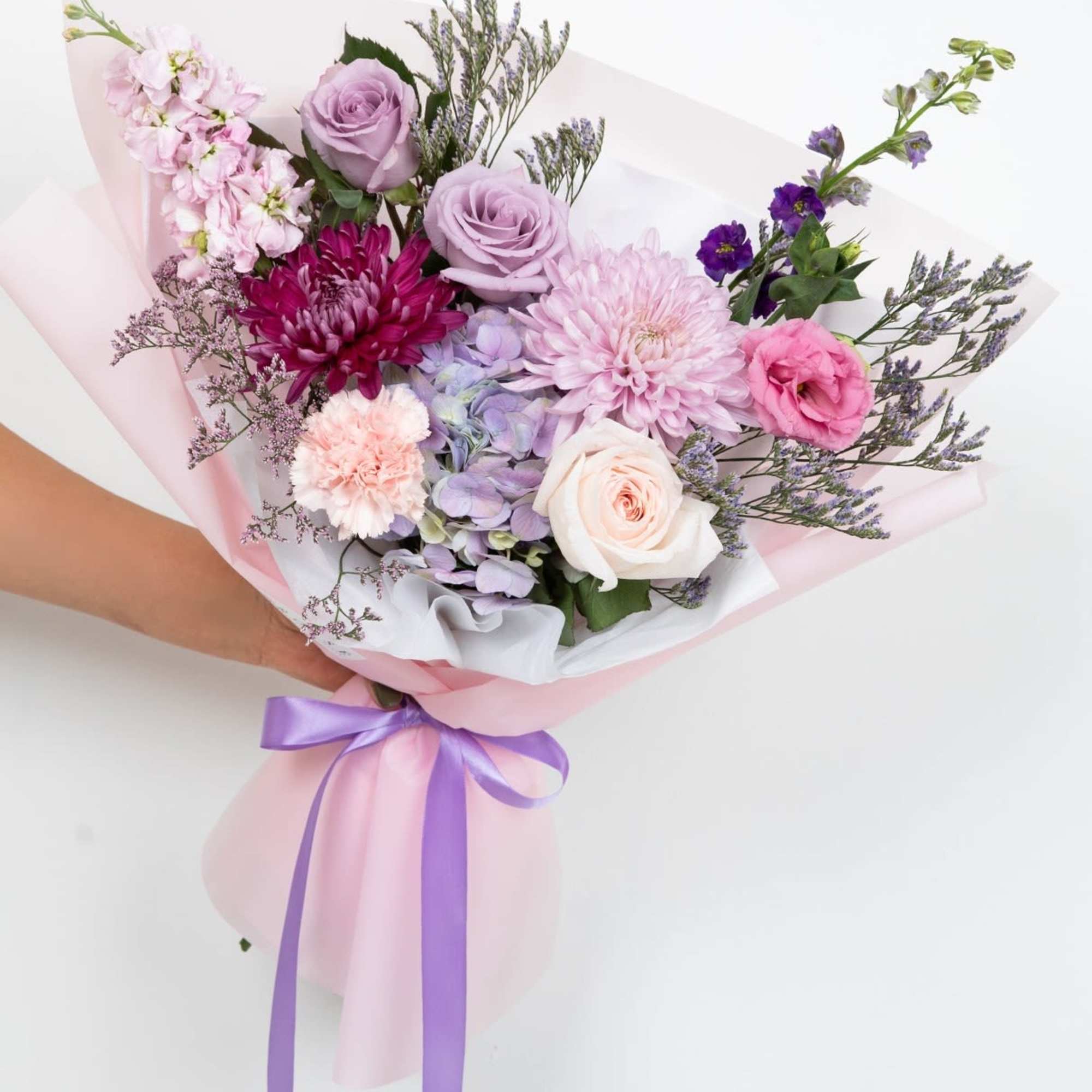A front-facing bouquet with different tones of lilac, lavender, and purple, wrapped