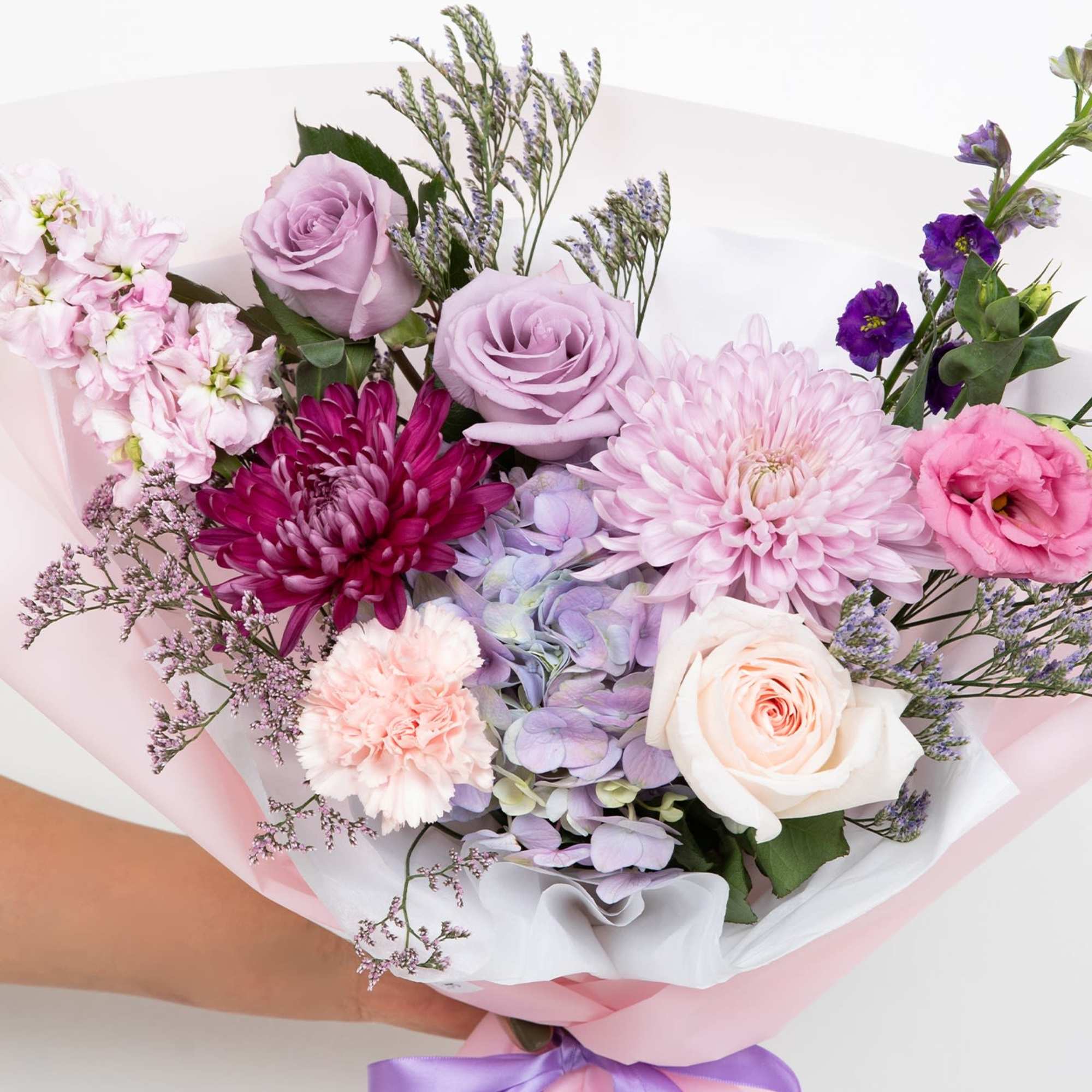 A front-facing bouquet with different tones of lilac, lavender, and purple, wrapped