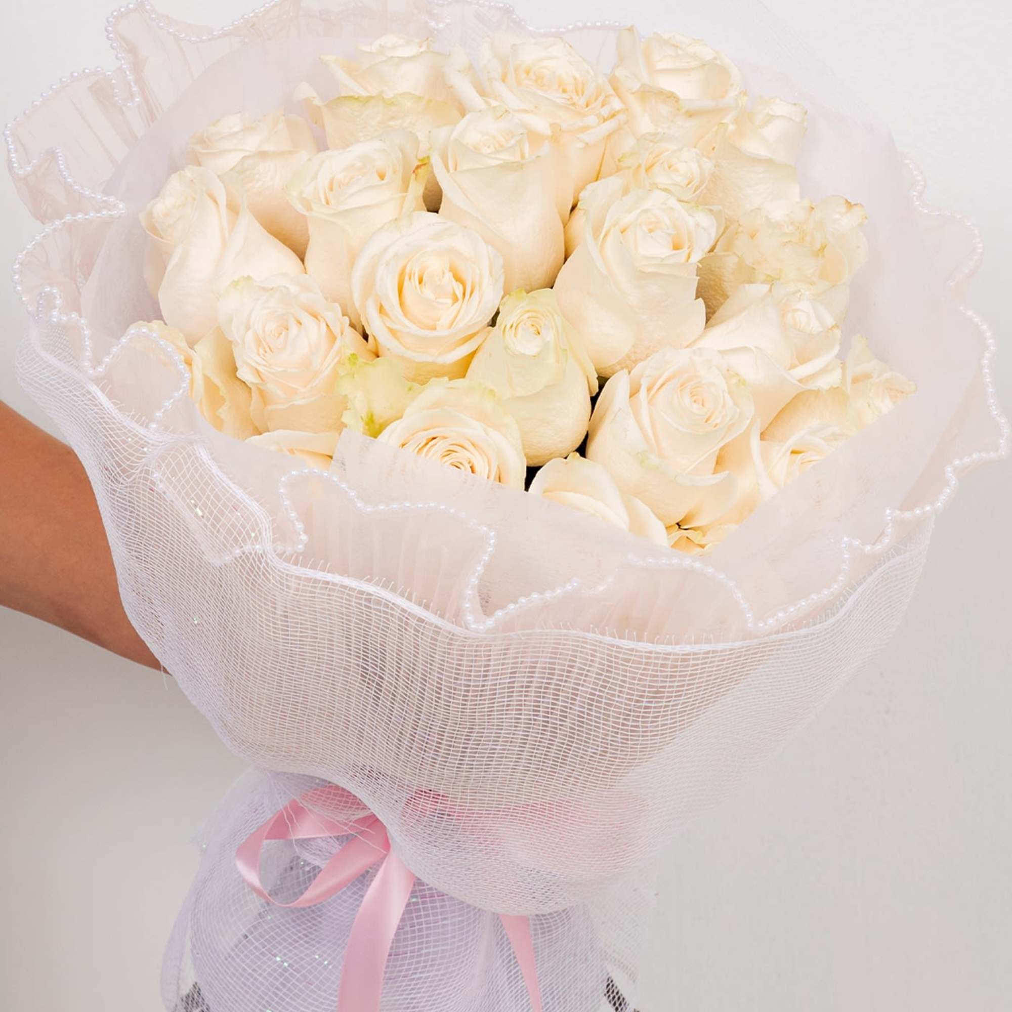 A round bouquet of two dozen roses. White mesh wrapping with a