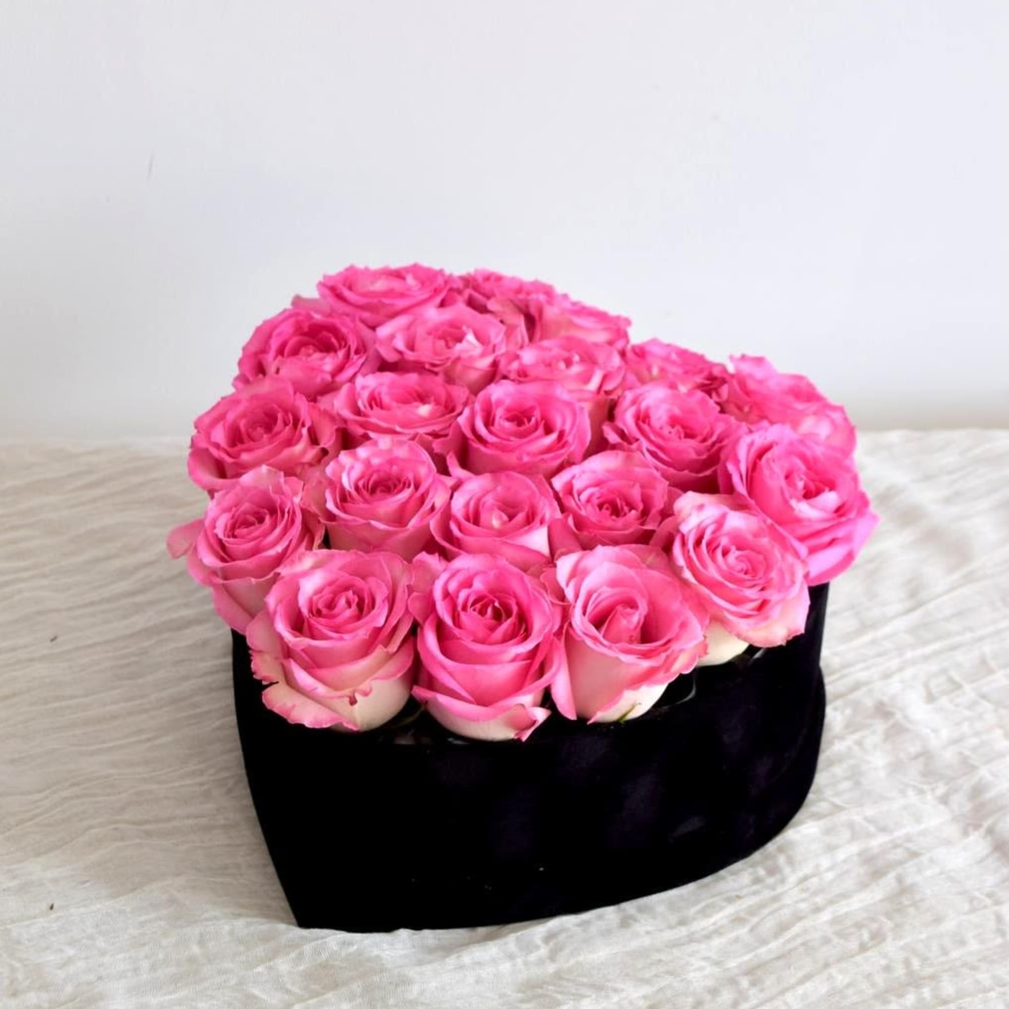 A black heart-shaped box filled with roses. 

Flower types may vary depending