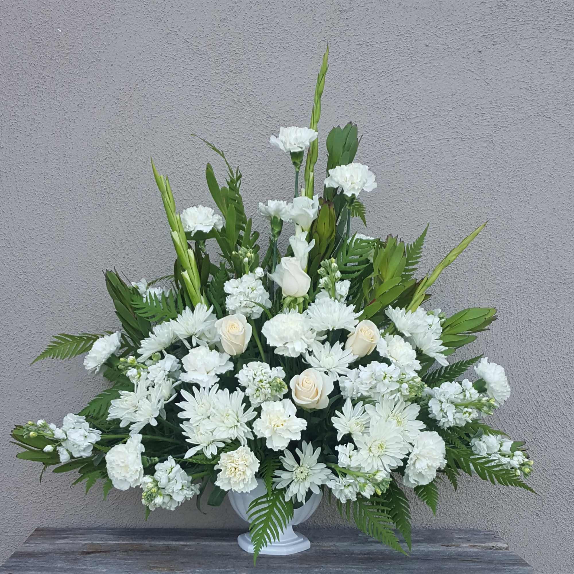 A traditional white funeral fan. Includes roses, carnations, mums, and other seasonal