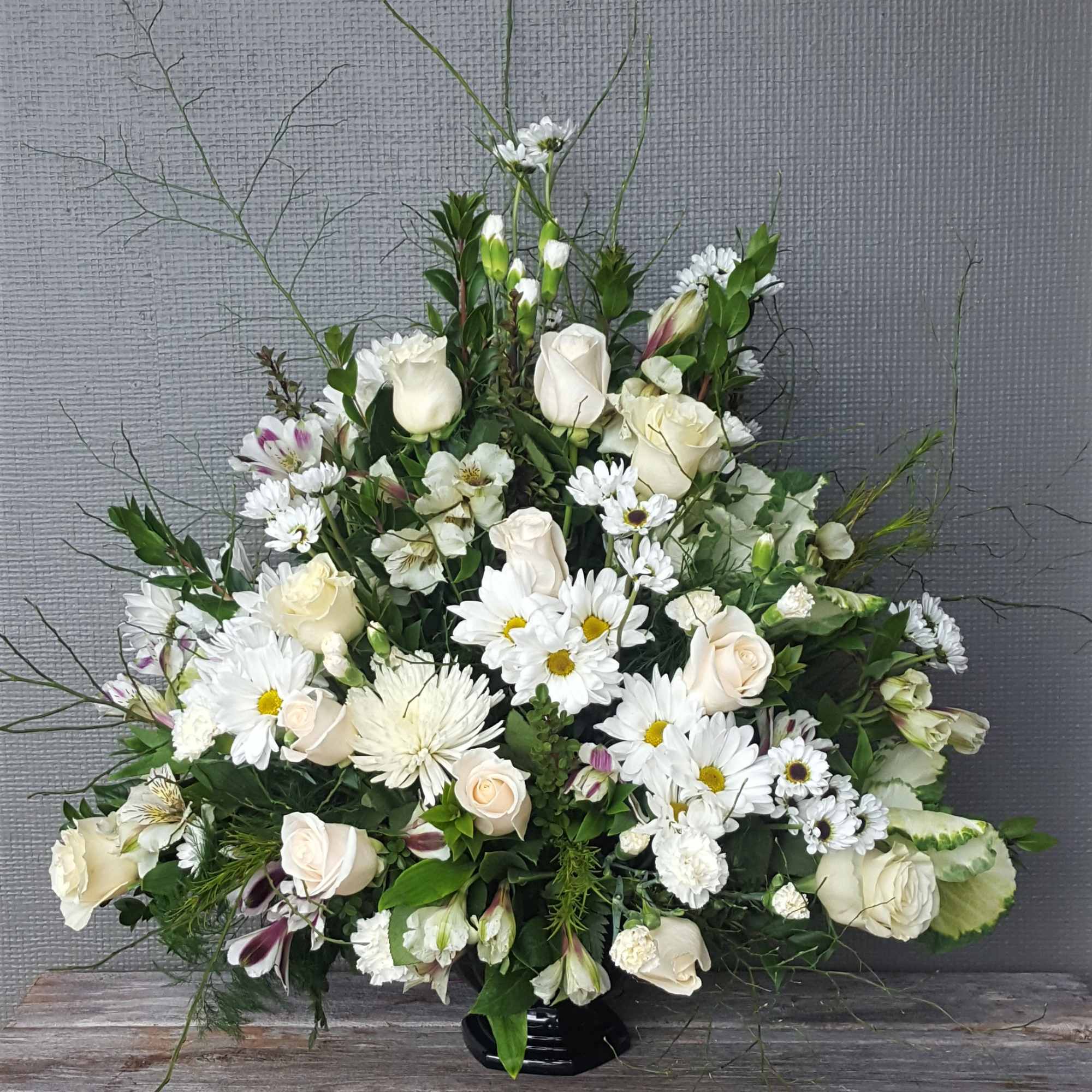 A traditional white funeral fan. Includes roses, carnations, mums, and other seasonal