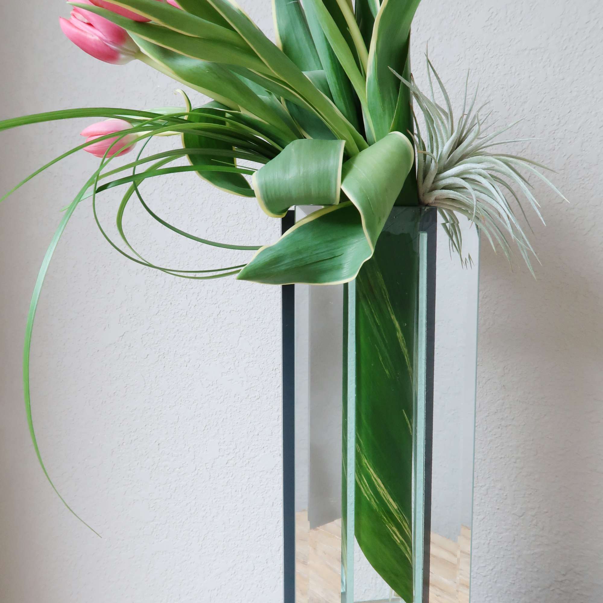 Tall mirrored vase filled with tulips accented with air plants and tropical