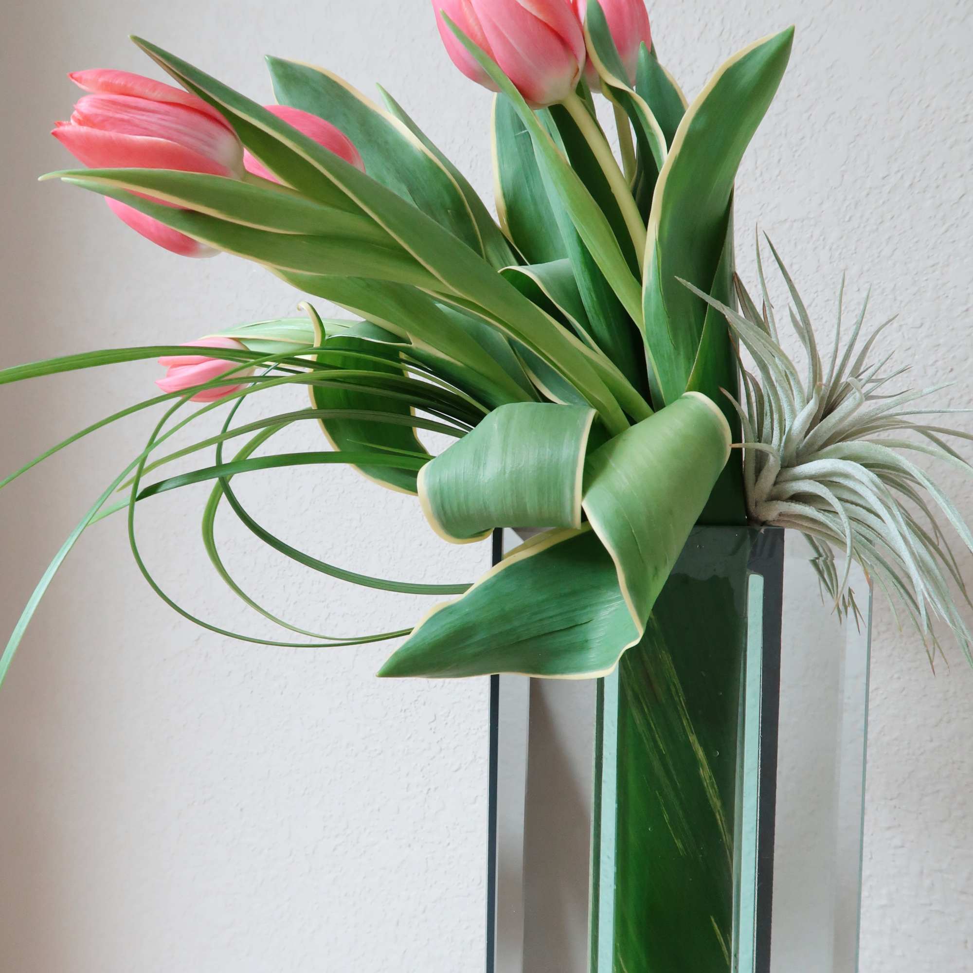 Tall mirrored vase filled with tulips accented with air plants and tropical