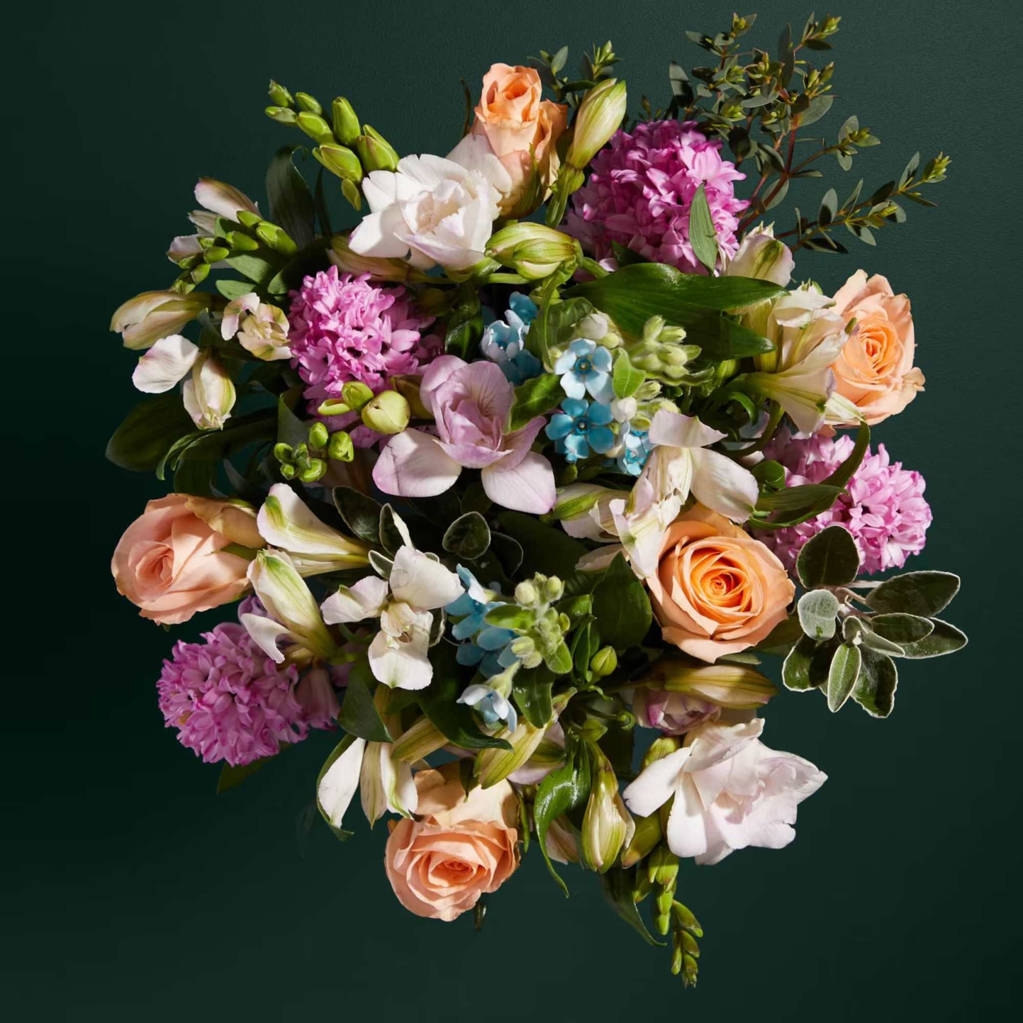 Mixed bouquet of peach roses, pink blooms, and white flowers
