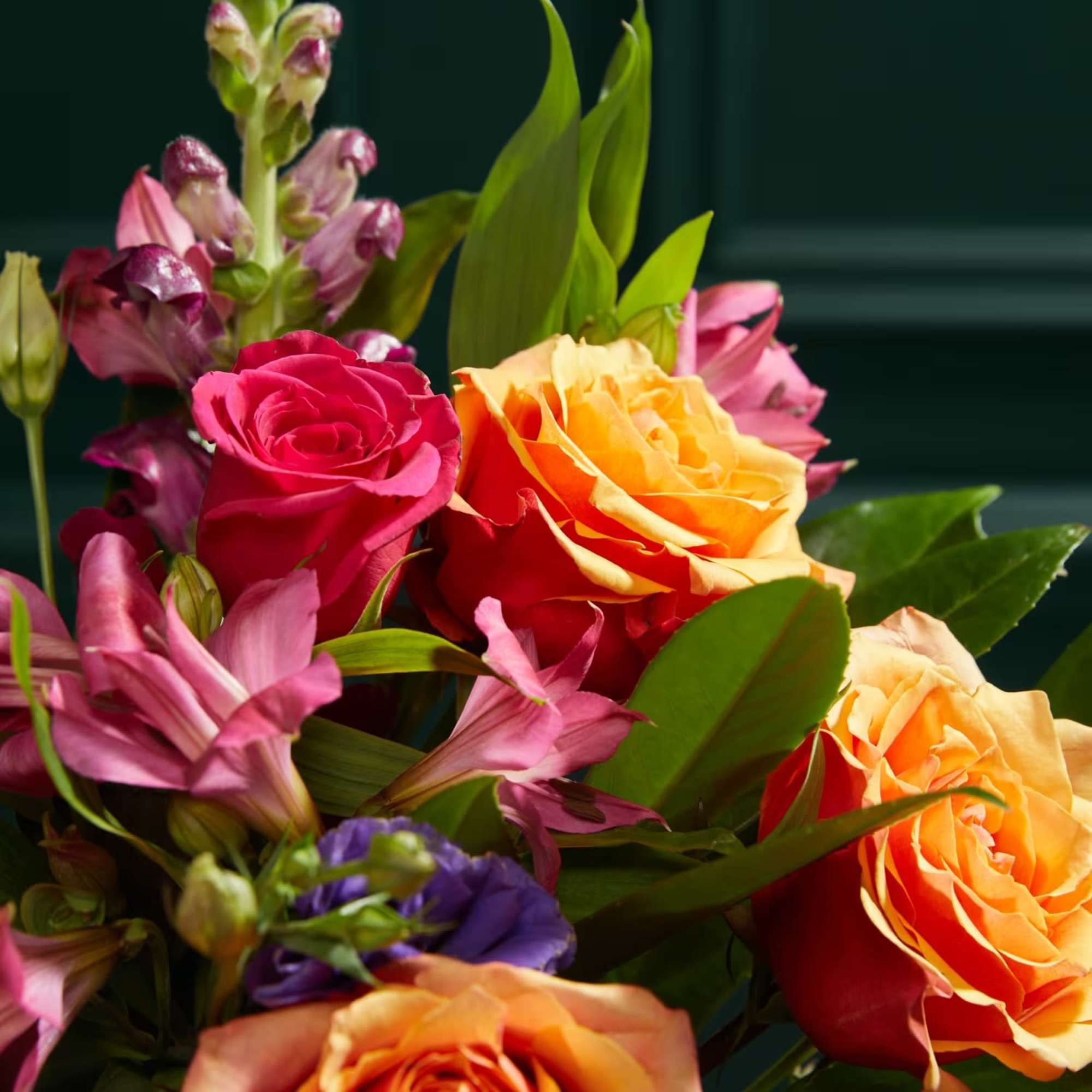 Bouquet of orange and pink roses with purple flowers