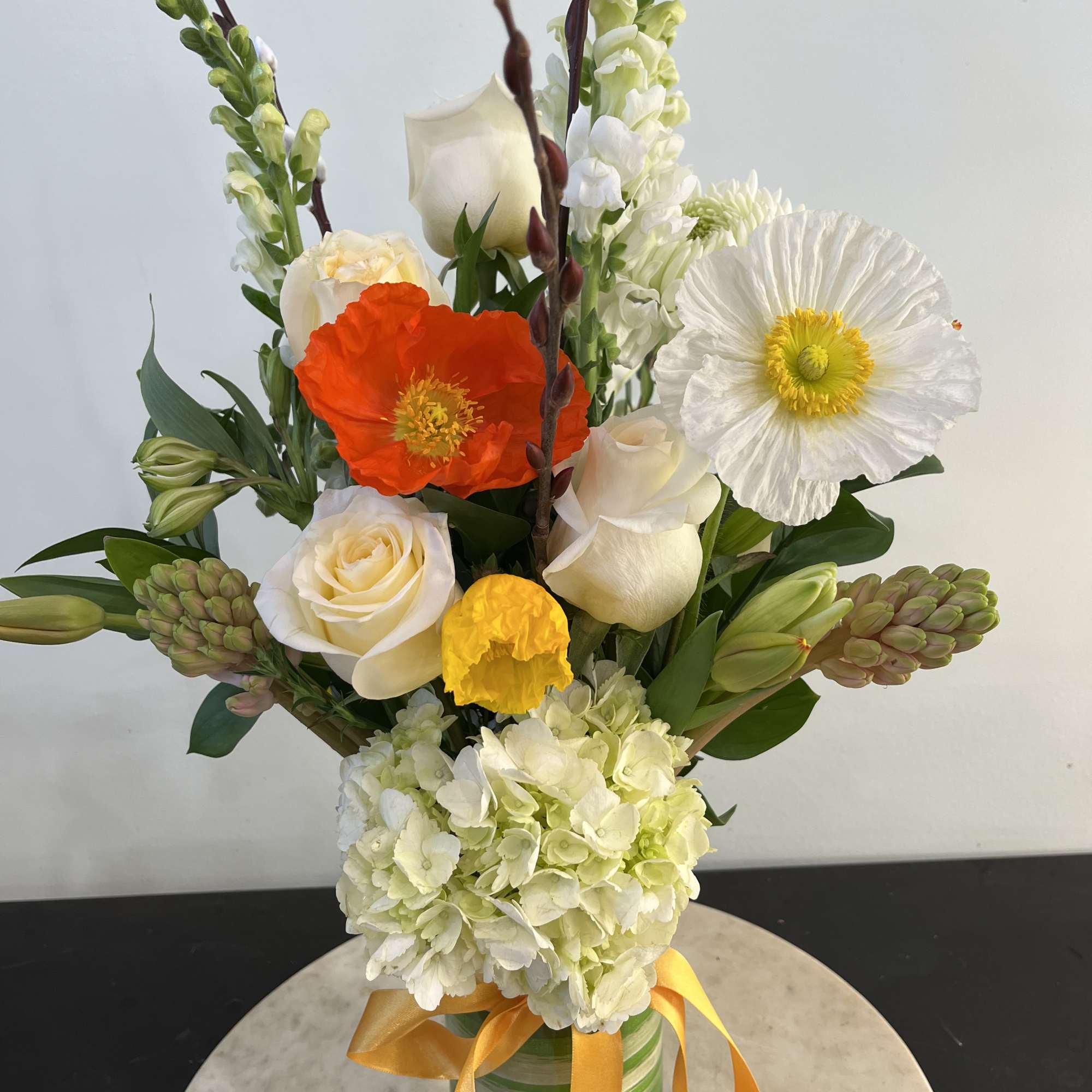A clear glass vase with flowers and farm greens. A special gift