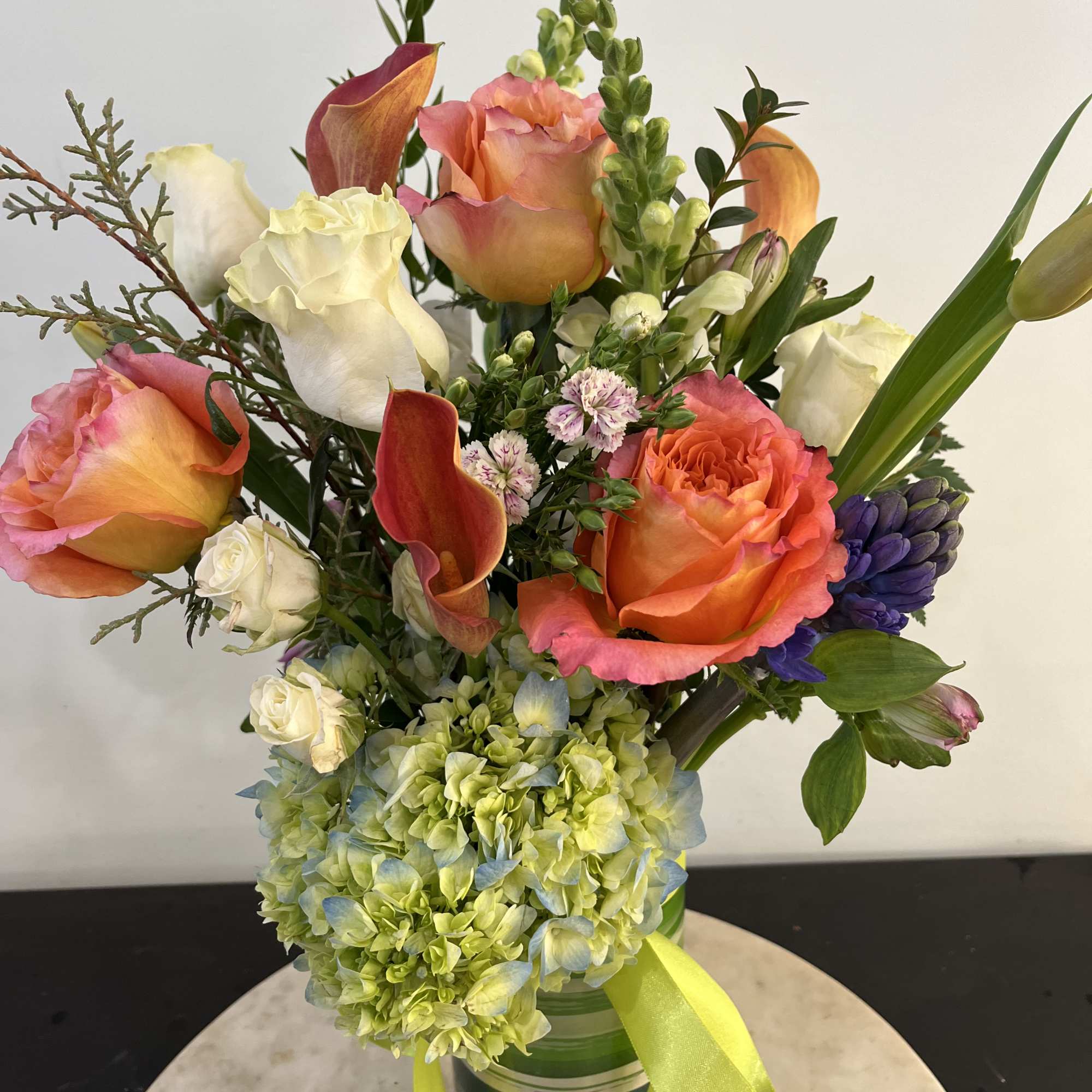 A clear glass vase with flowers and farm greens. A special gift