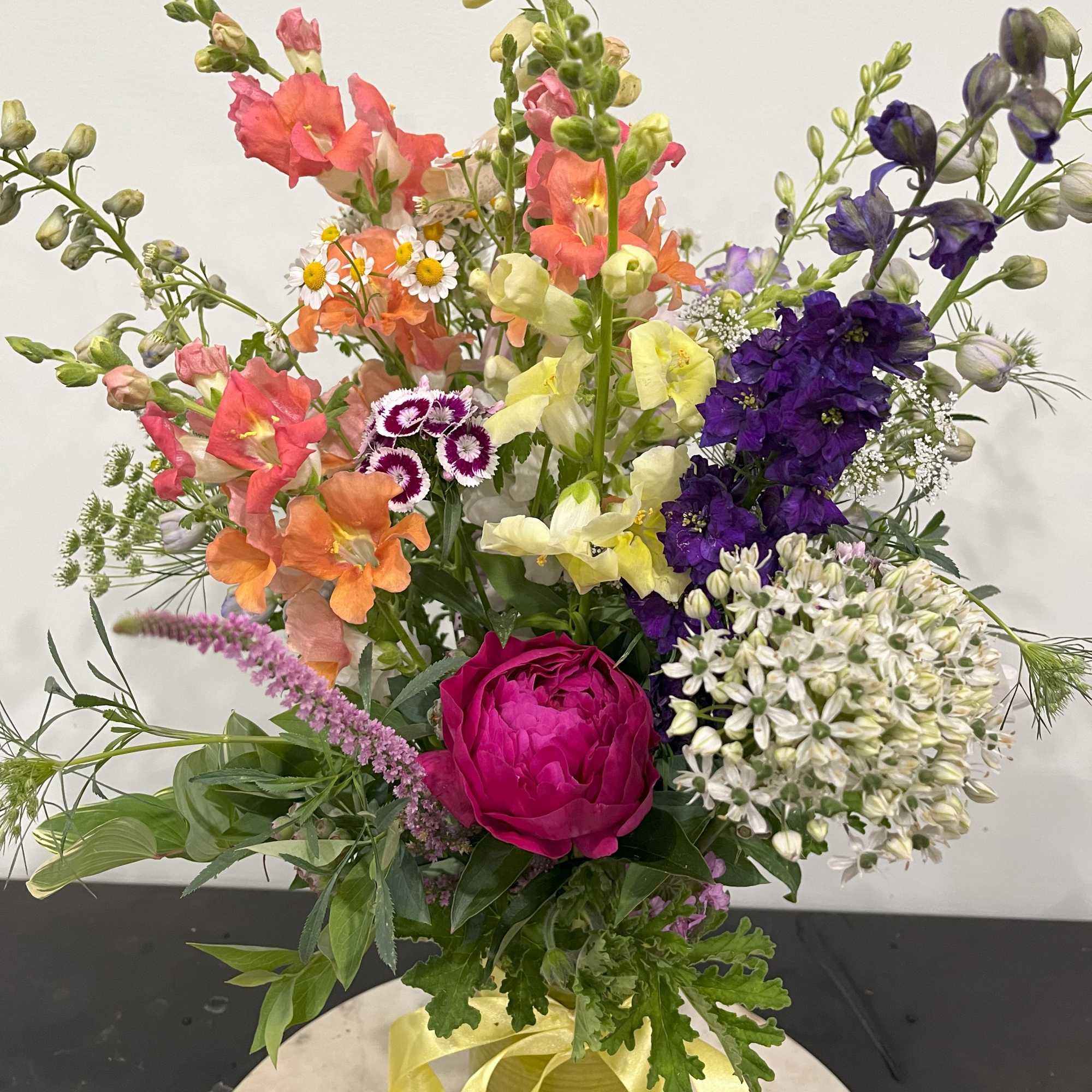 A clear glass vase with flowers and farm greens. A special gift