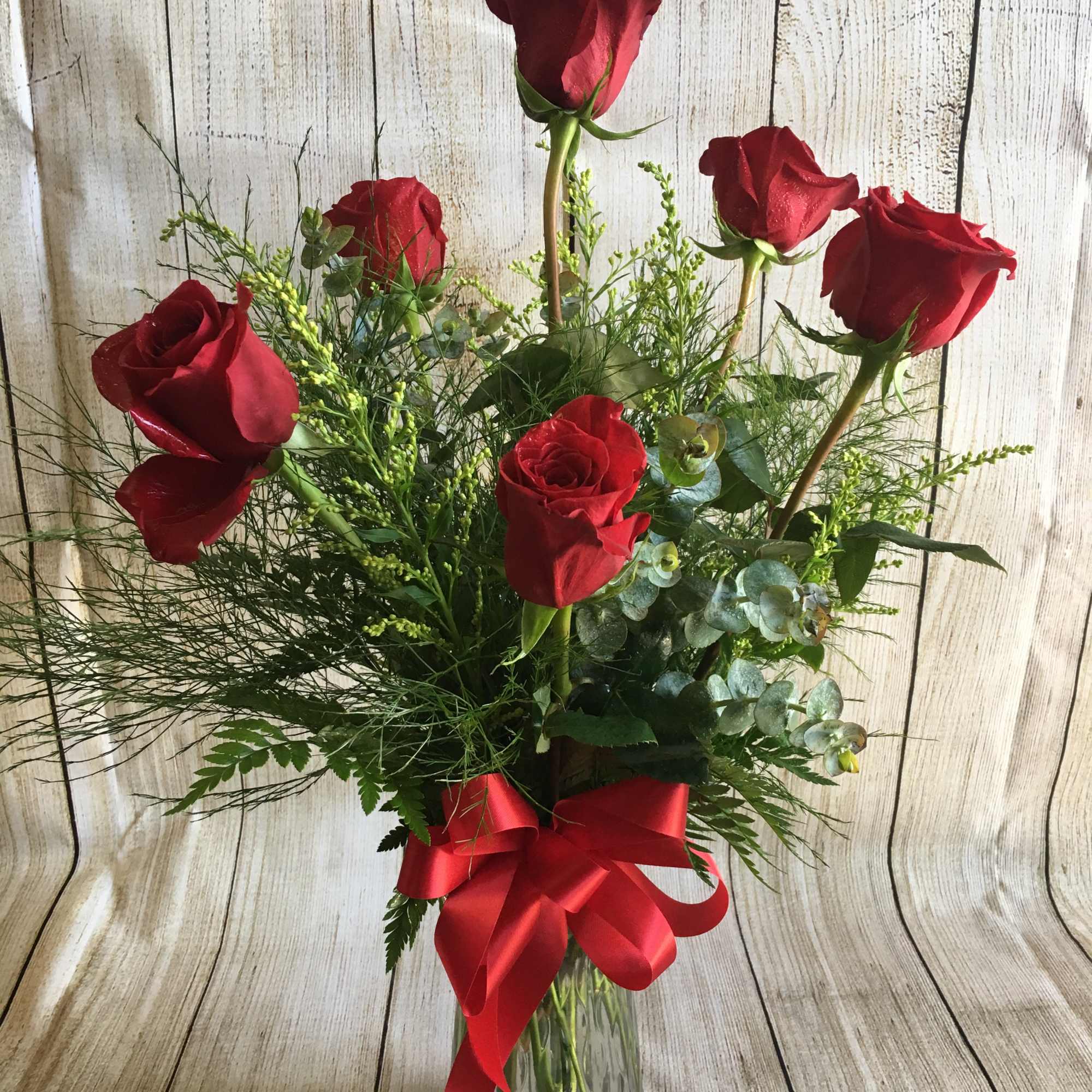 6 Red roses traditionally designed in a glass vase with filler and