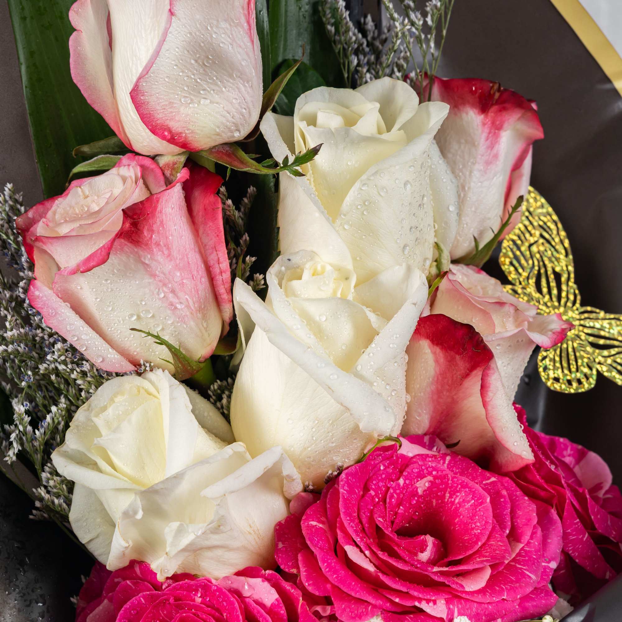 A luxurious bouquet of pink-edged white roses and vibrant pink blooms, wrapped