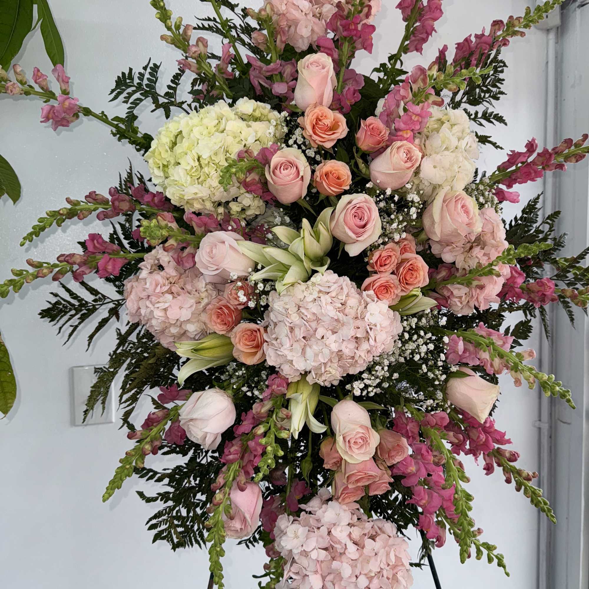 Pink roses, lilies, and more come together for a blushing pink standing