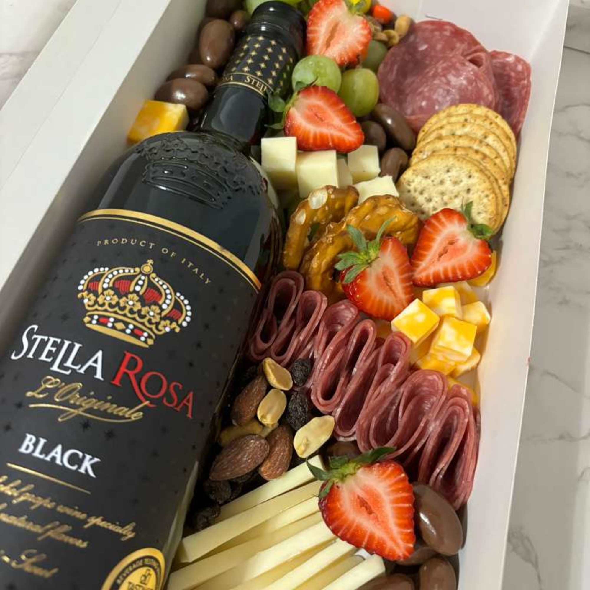 Different cheeses, meats, fruits, crackers. Stella Rose Black Bottle 