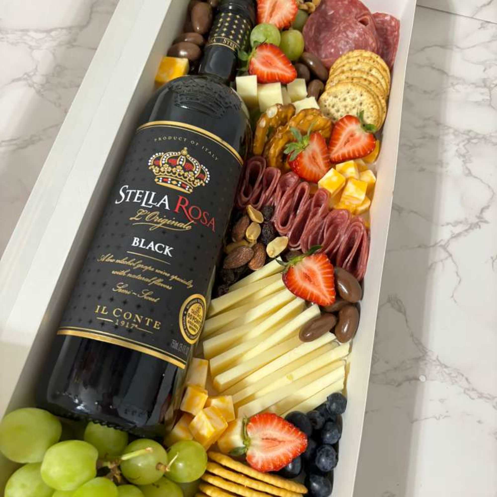 Different cheeses, meats, fruits, crackers. Stella Rose Black Bottle 
