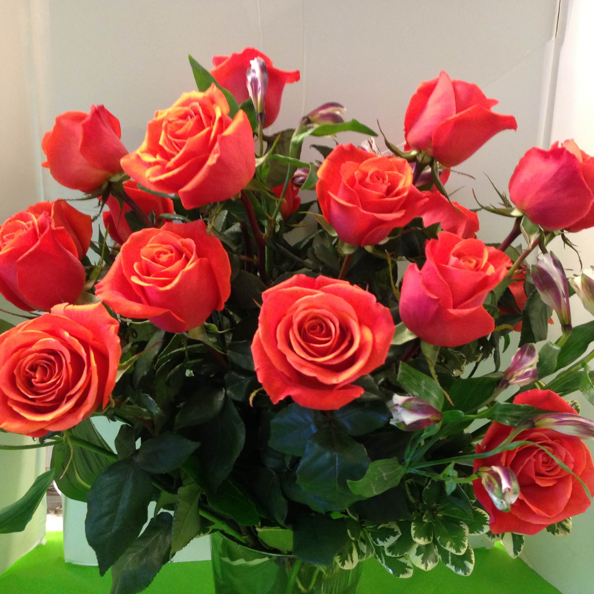  Orange Roses, Assorted Fancy greens, in a Tall Glass Vase