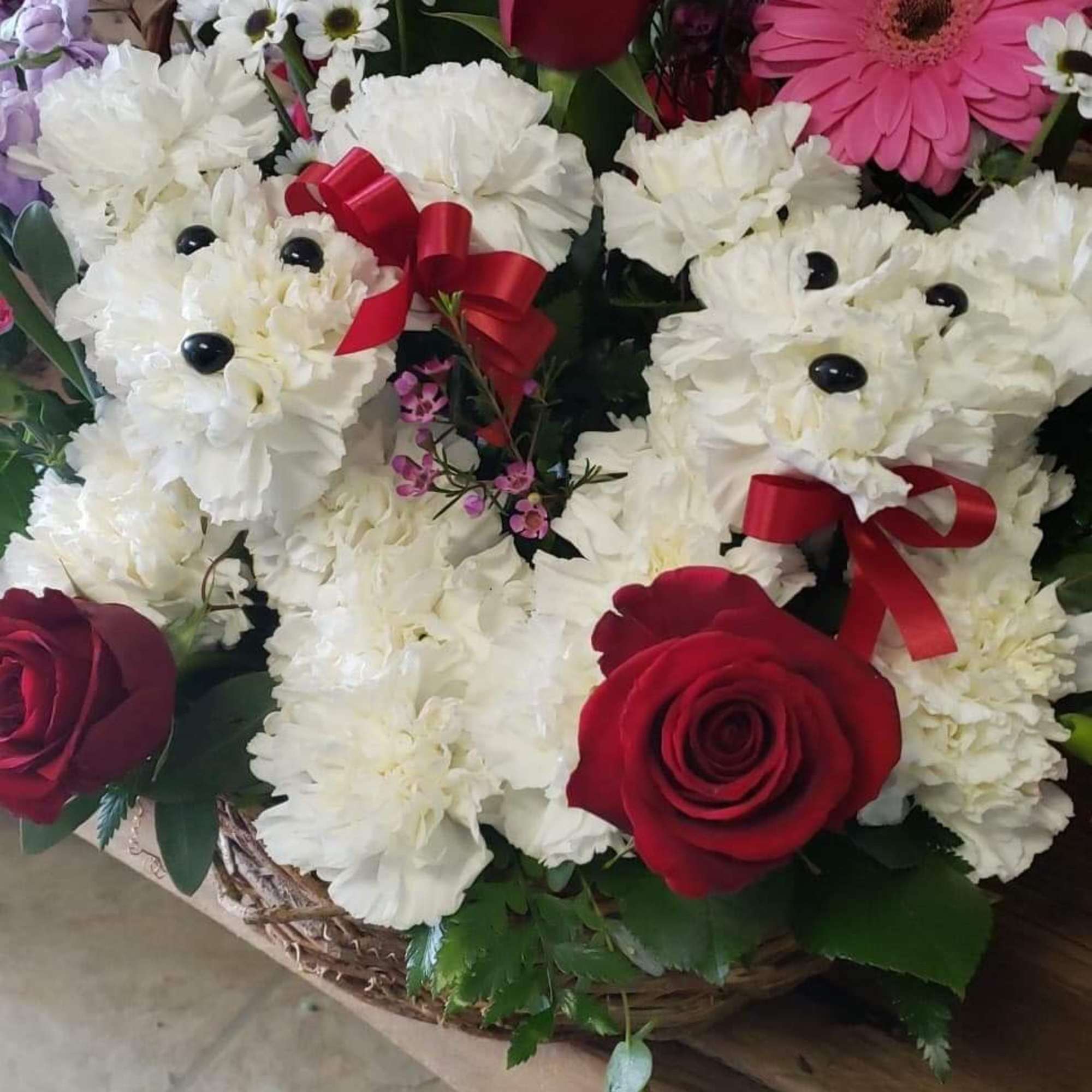 Basket arrangement with white teddy bears, red roses, and pink gerbera daisies