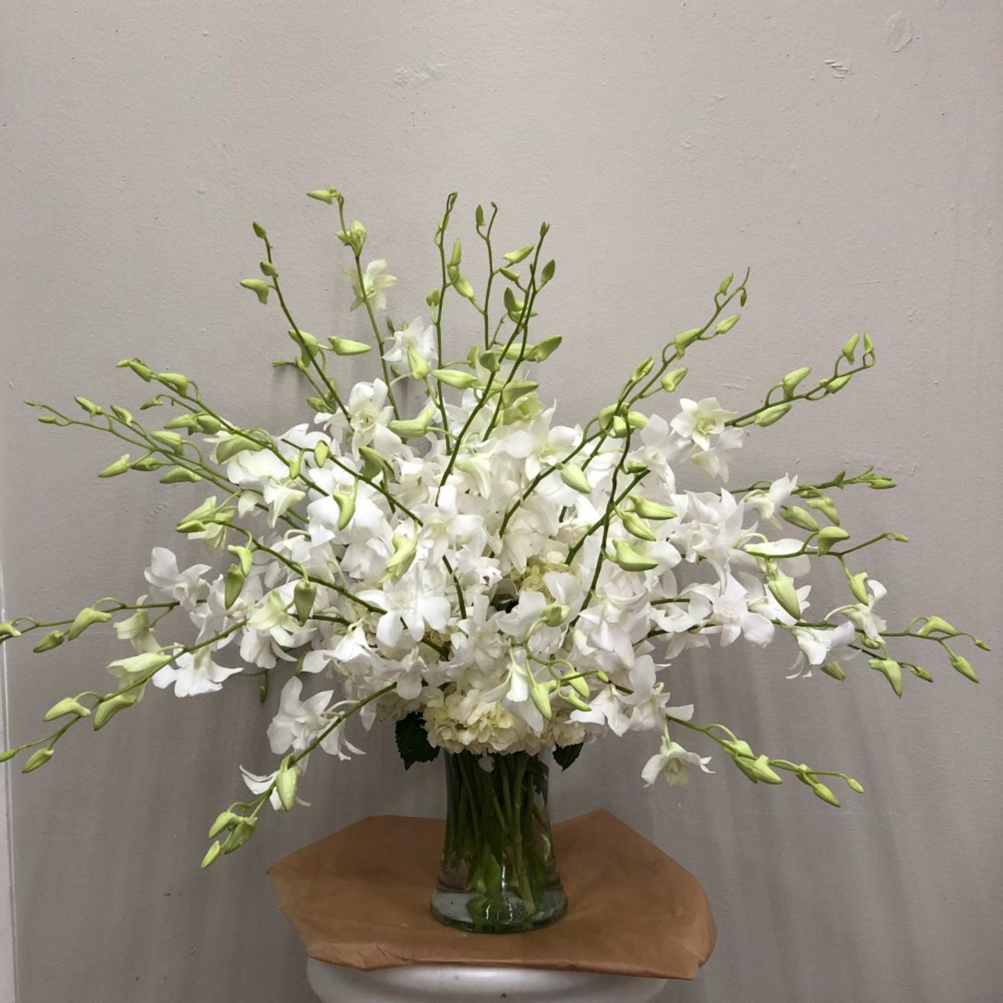 Clear vase full of cut white Dendrobium Orchids &amp; hydrangeas. Colors and