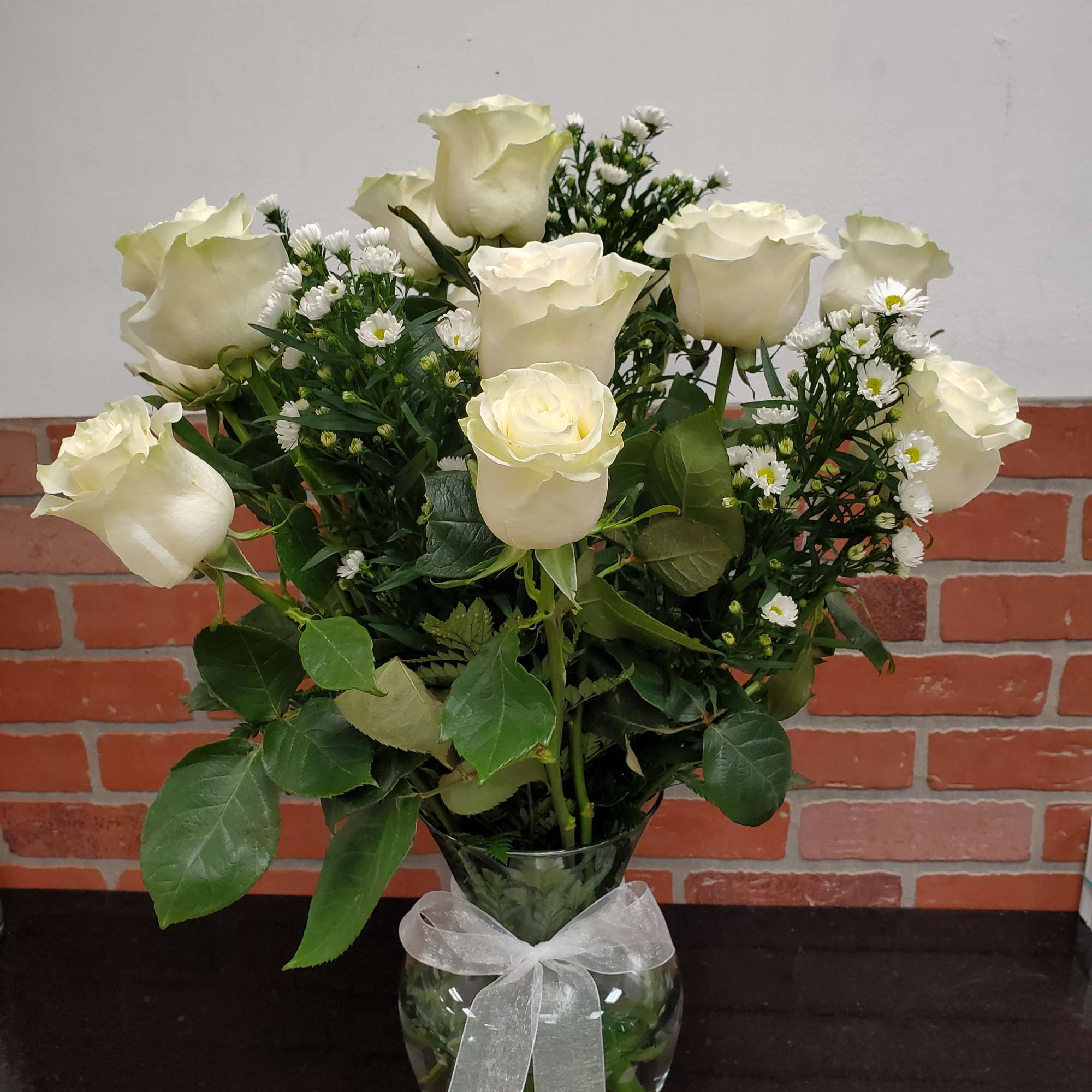 12 white roses in a nice clear vase with white monte casino