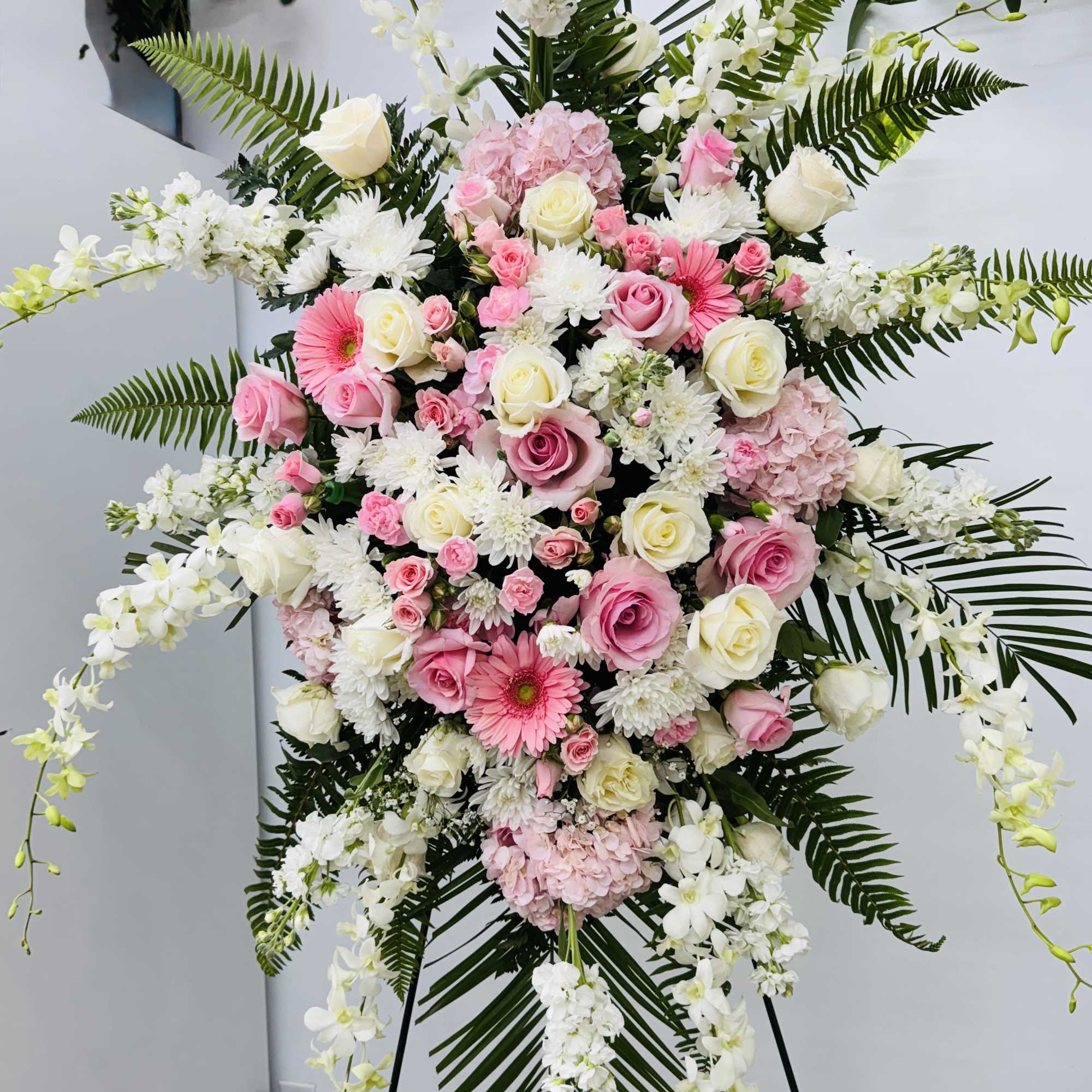 Large standing floral spray with pink and white flowers on an easel