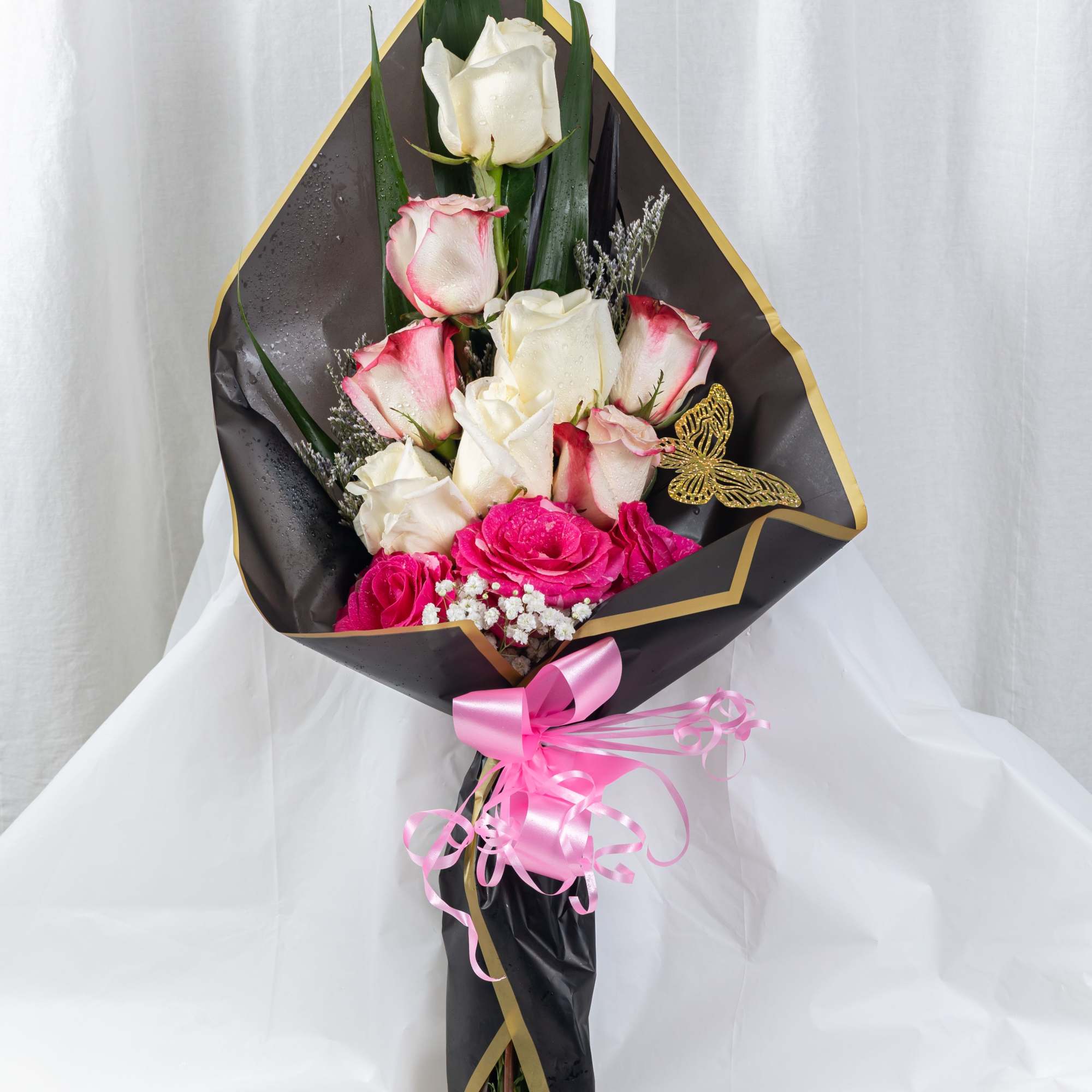 A luxurious bouquet of pink-edged white roses and vibrant pink blooms, wrapped