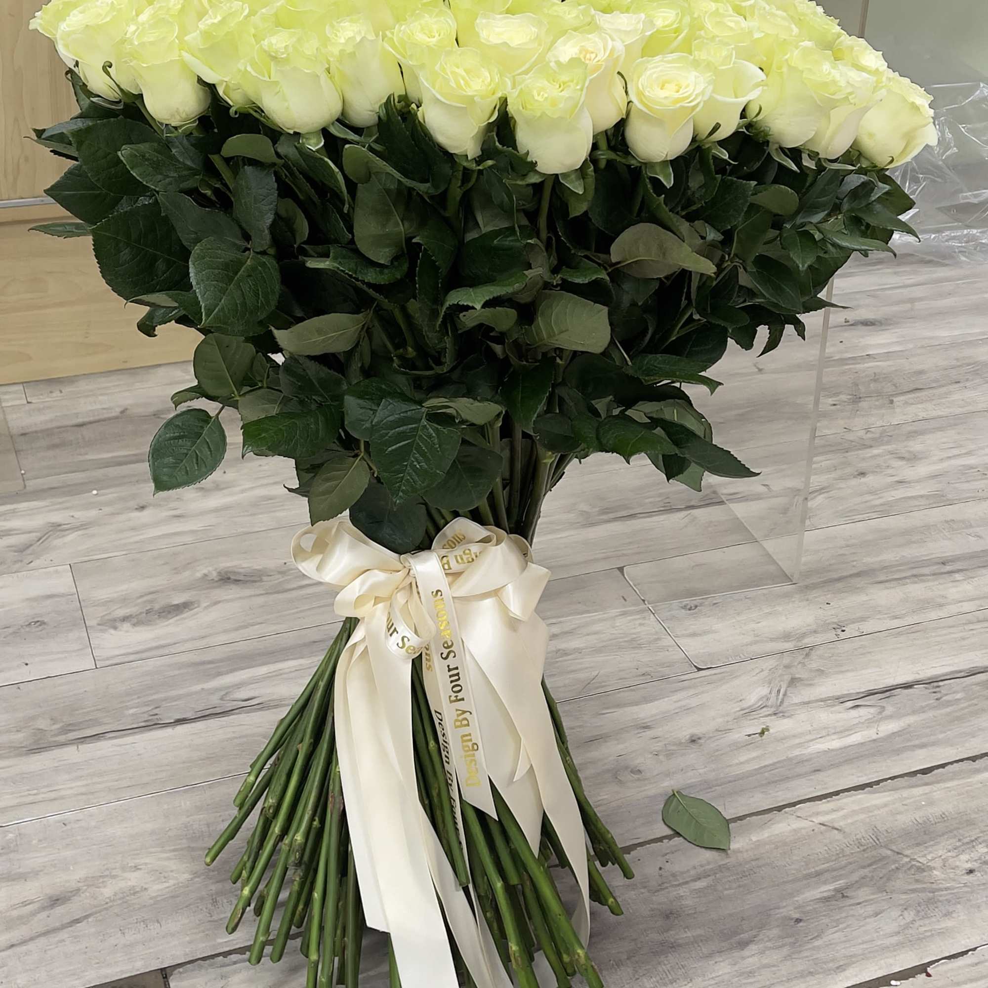 A breathtaking bouquet of 100 fresh white roses, beautifully hand-tied with lush