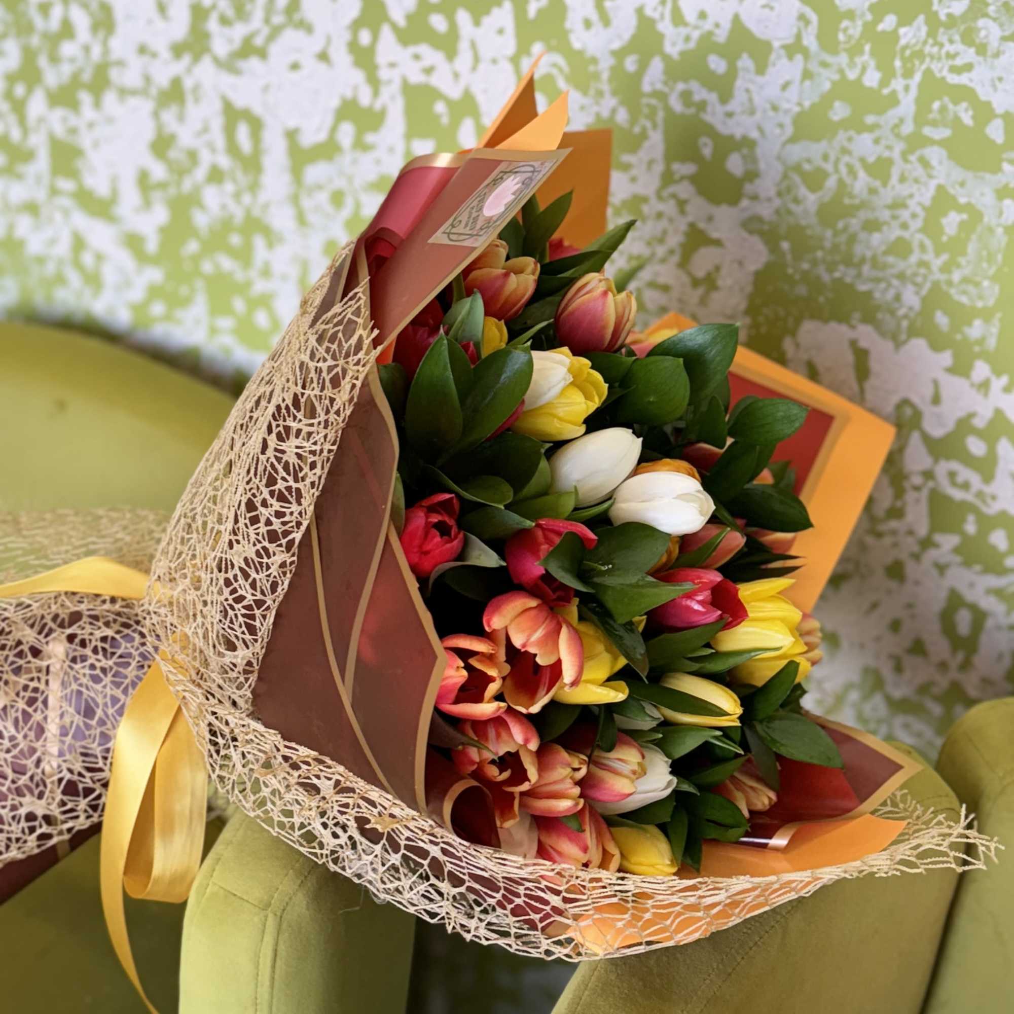 A warm and cheerful bouquet of vibrant tulips wrapped in elegant golden