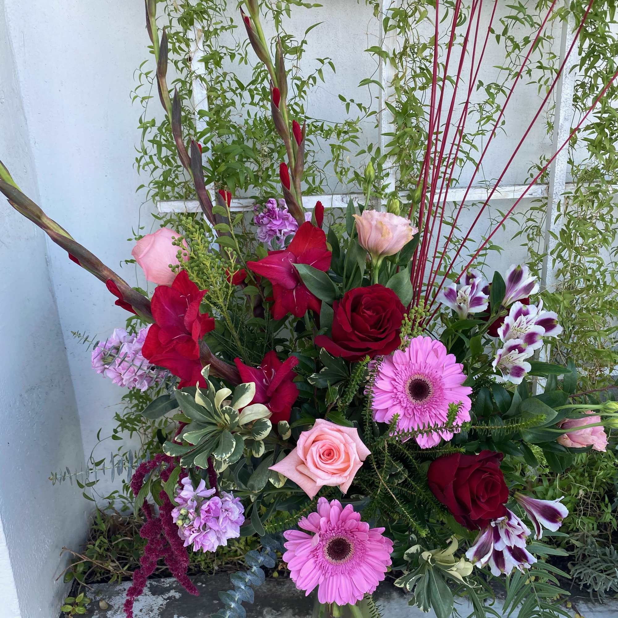 Shades of pinks and burgundies, gerbers, roses, stock, etc. 
&ldquo;Subject to flower