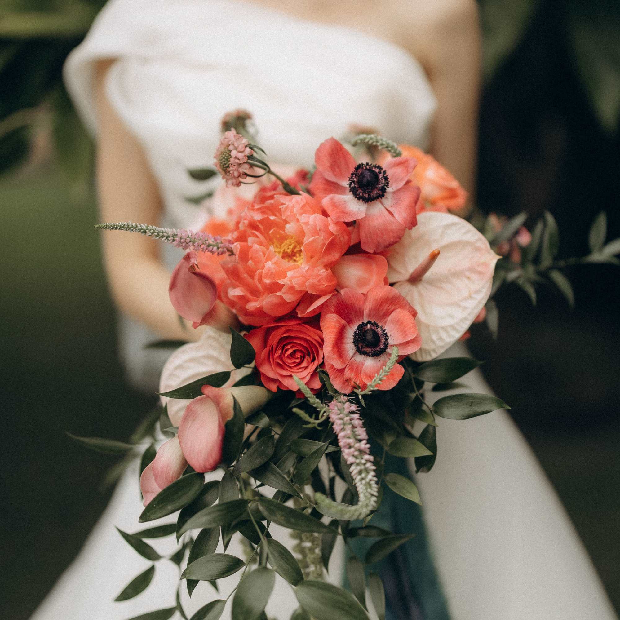 A bride in a classic white gown holds a lush bouquet bursting