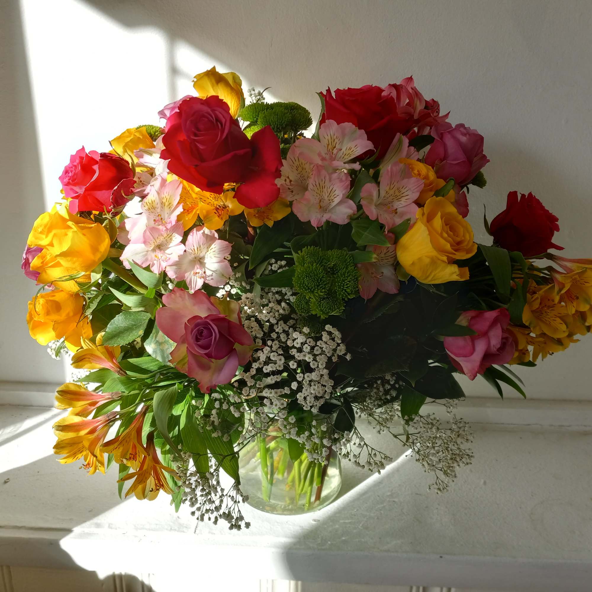 Colorful mixed colors roses in a vase with Alstroemeria, baby's breath and