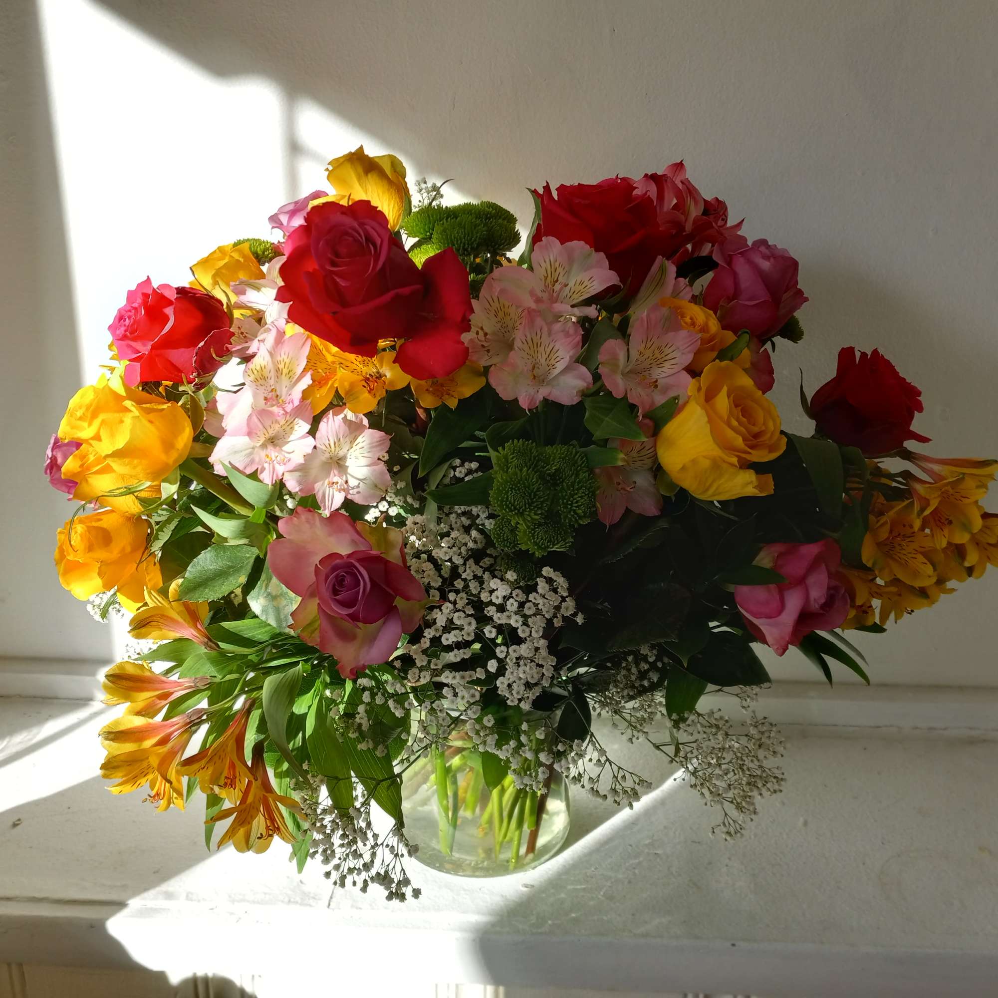 Colorful mixed colors roses in a vase with Alstroemeria, baby's breath and