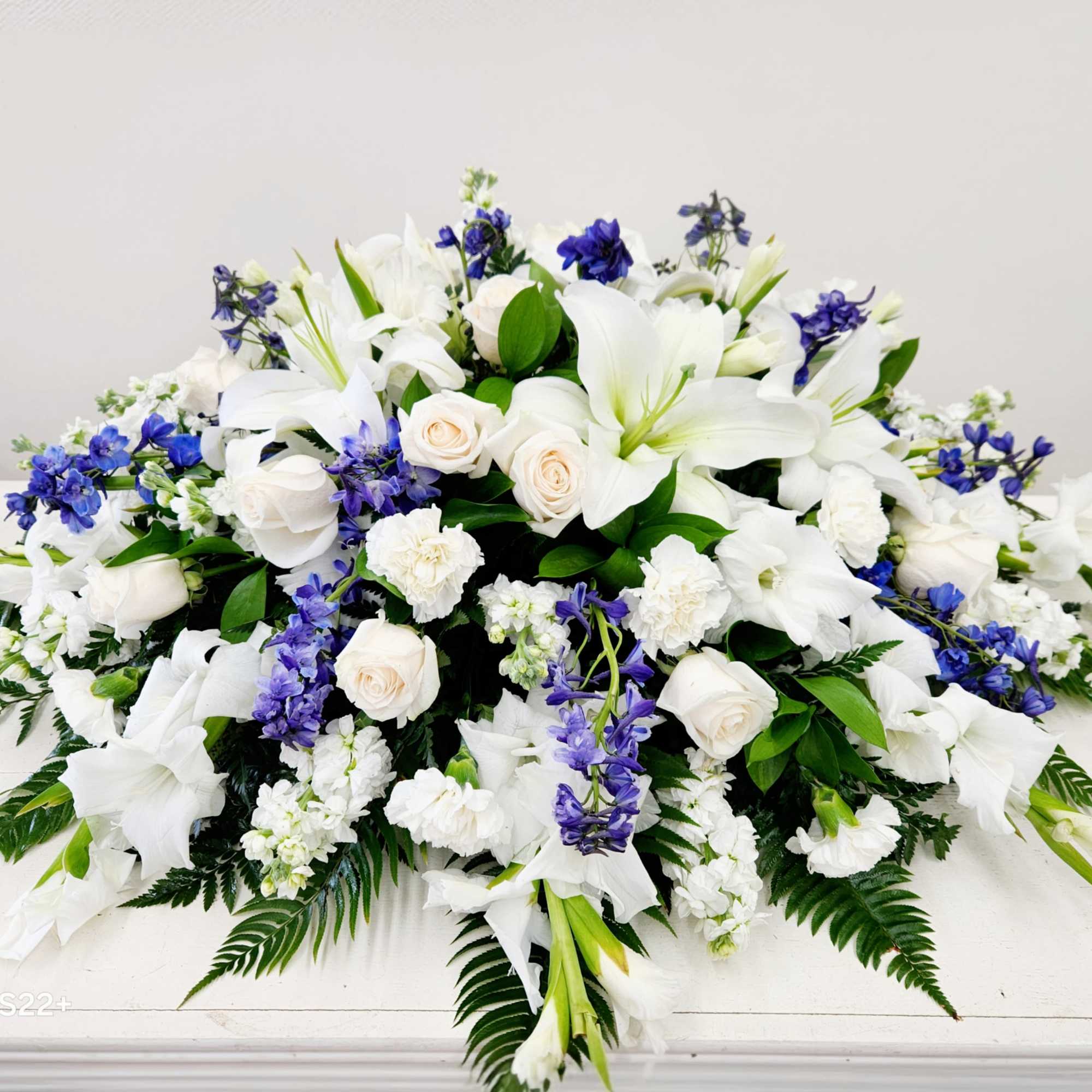 This Blue and White Casket Spray offers a timeless, elegant tribute crafted
