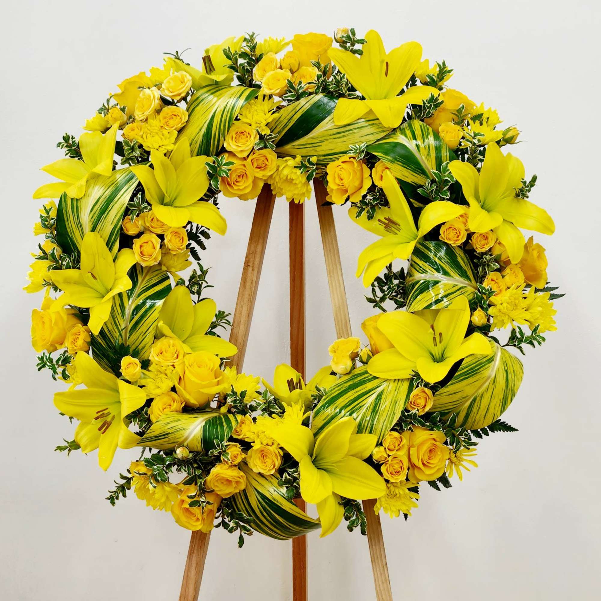 Sunny Remembrance Wreath is a luminous tribute featuring bright yellow roses and