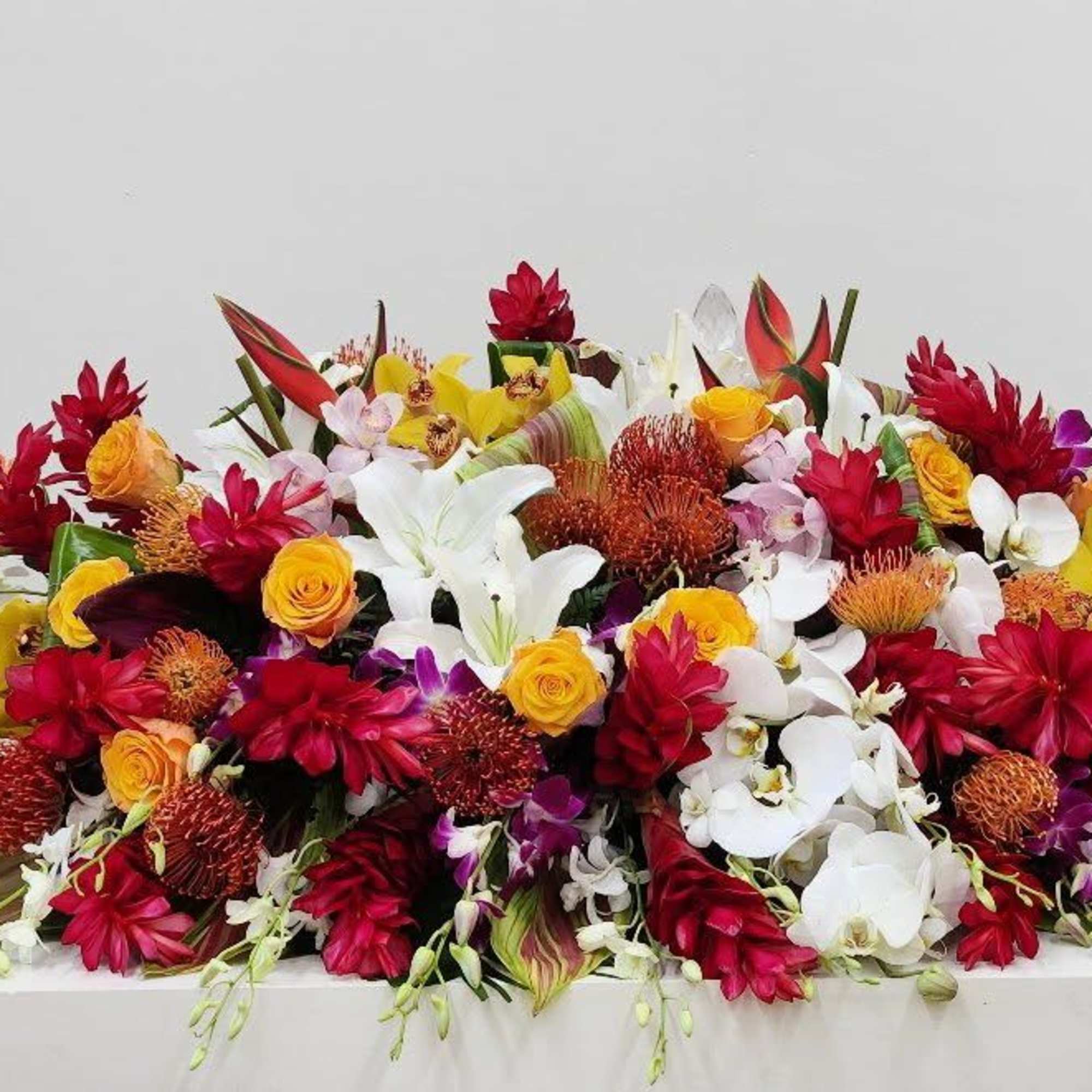 A luxurious and one-of-a-kind tropical casket spray, bursting with vibrant color and