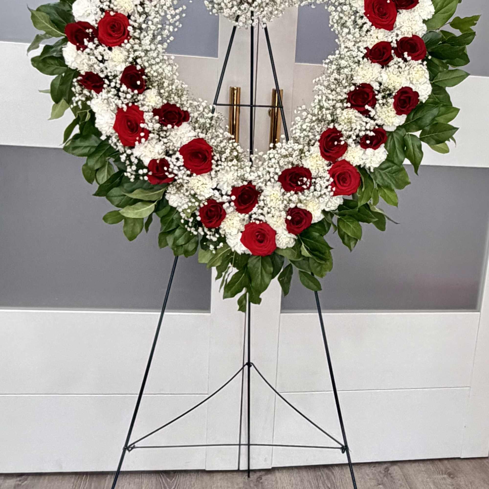 Heart-shaped red and white rose wreath on a stand