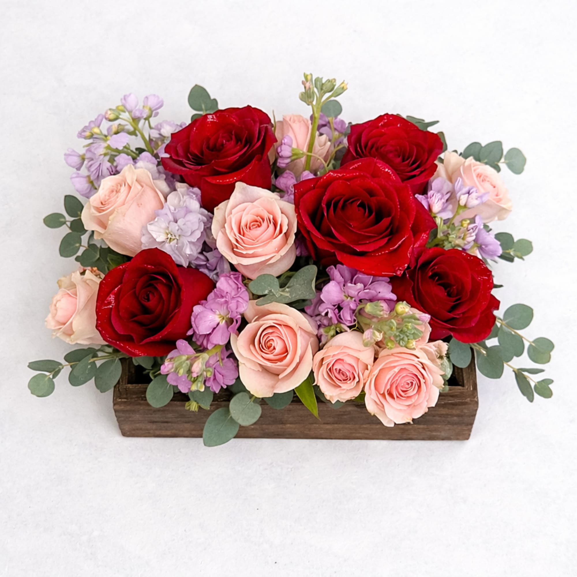 A romantic wooden flower box featuring a vibrant mix of red and