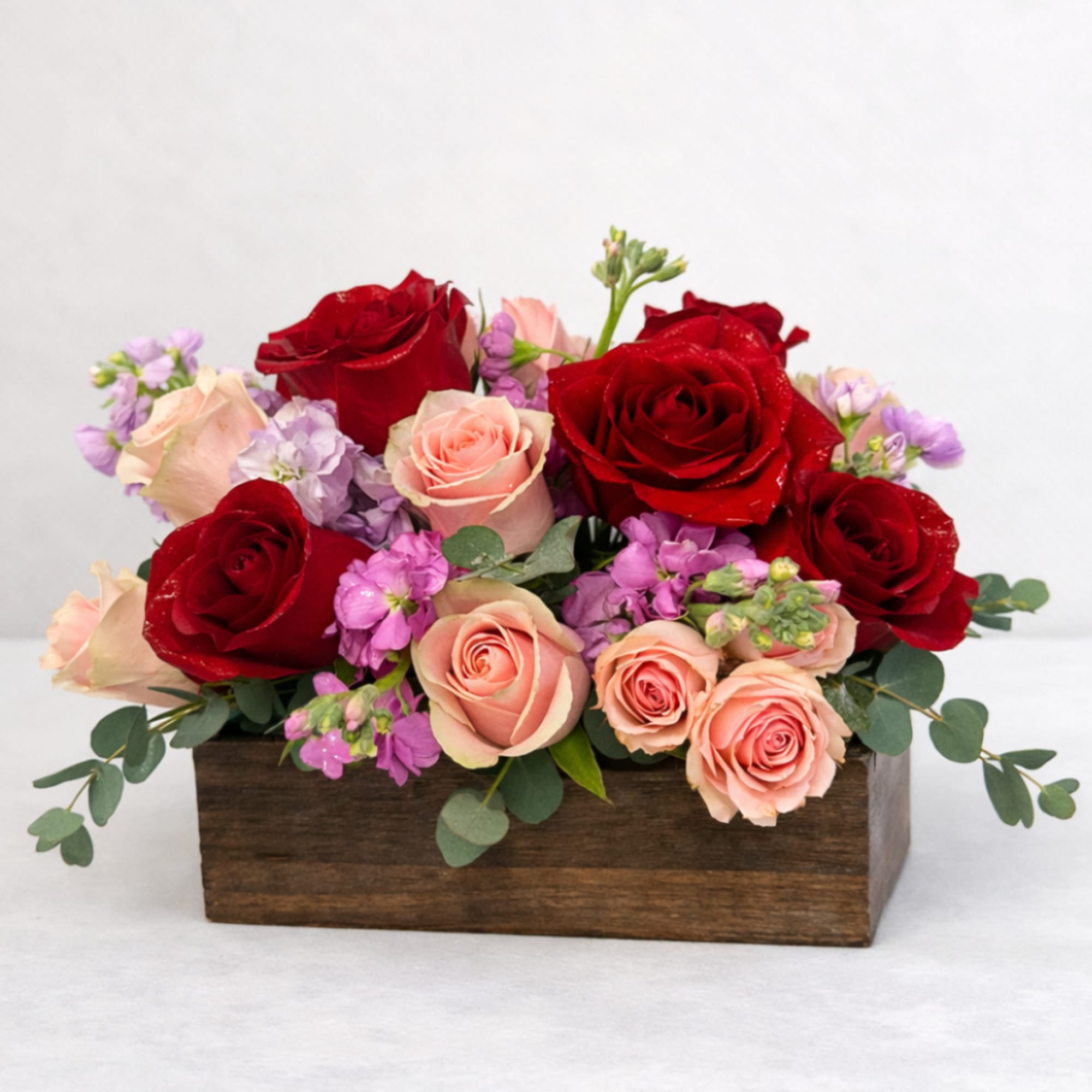 A romantic wooden flower box featuring a vibrant mix of red and