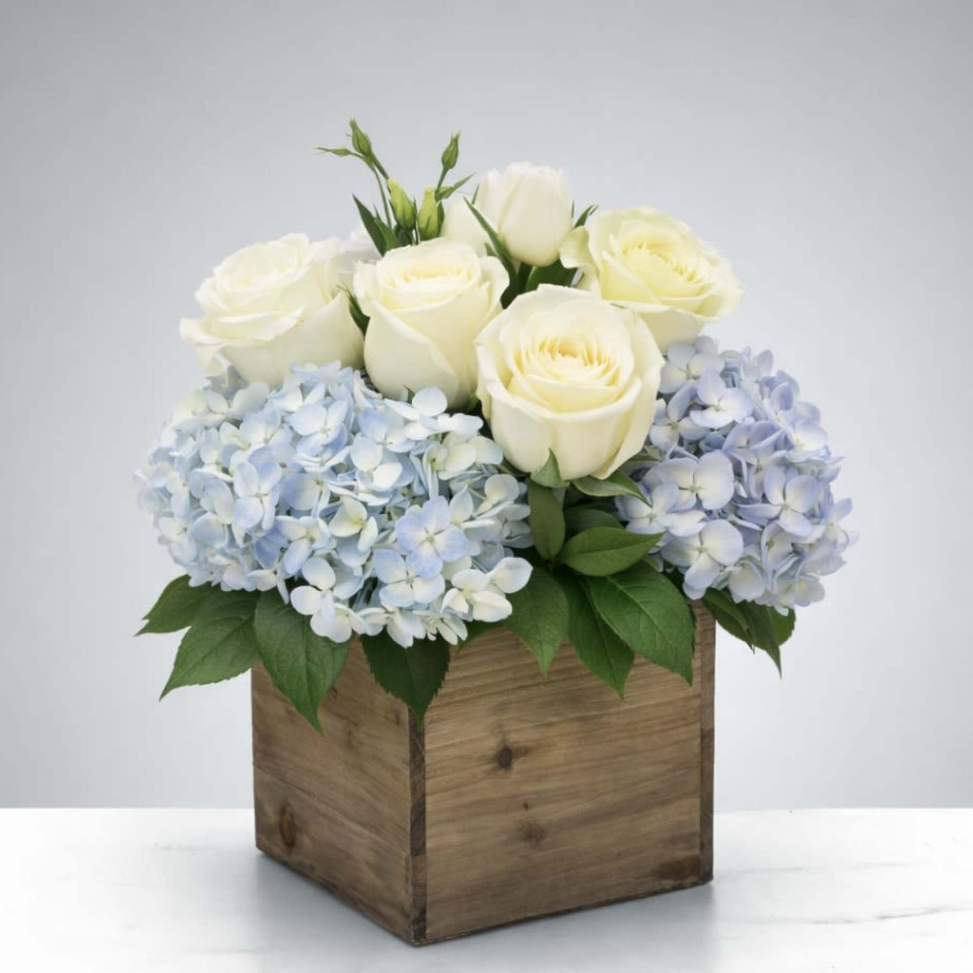 Soft blue hydrangeas paired with creamy white roses, designed in a rustic