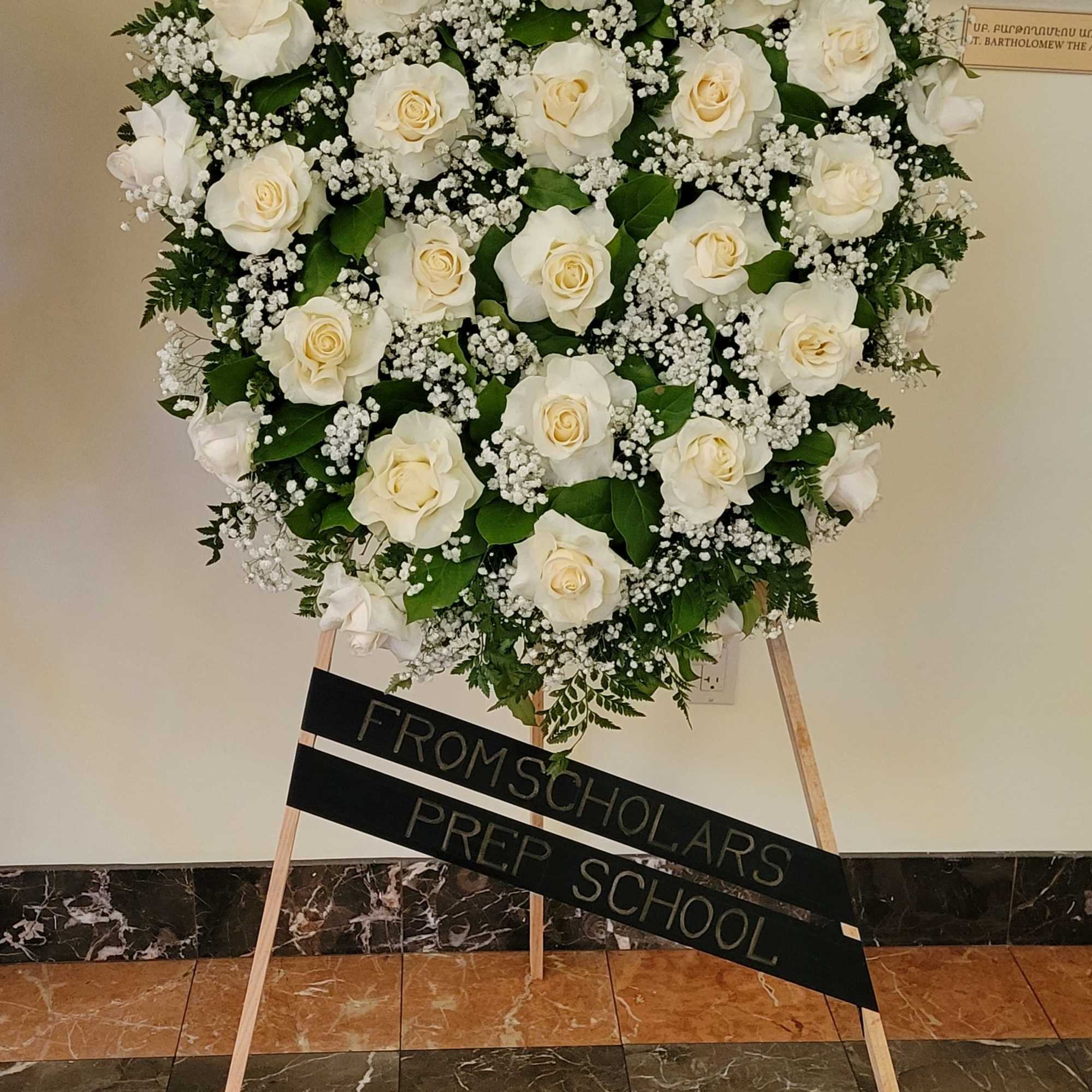 This elegant oval funeral wreath is composed of pure white roses and