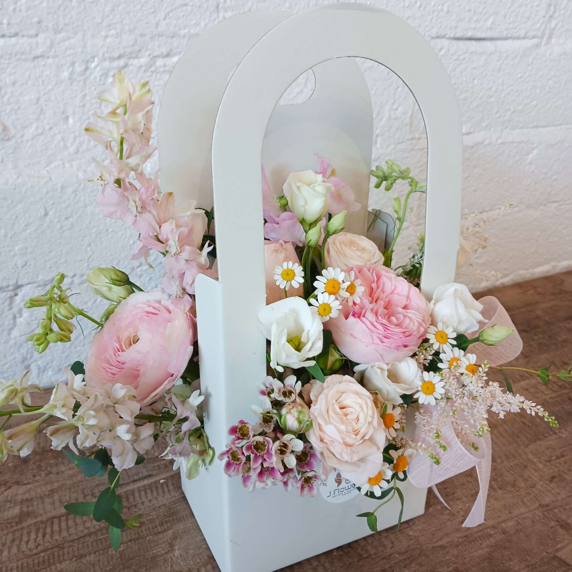 Designed in a flower box, this arrangement overflows with soft shades of