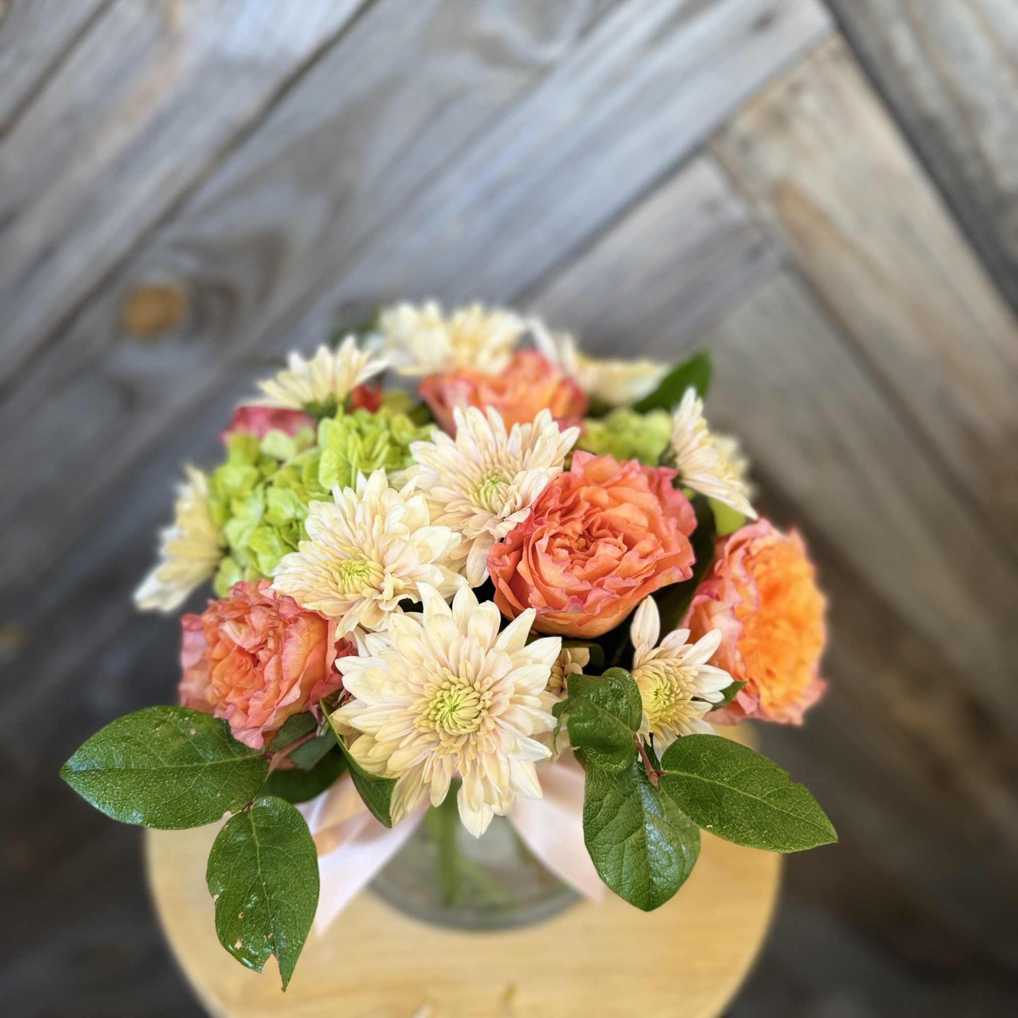 Bouquet of peach roses and cream daisies in a glass vase
