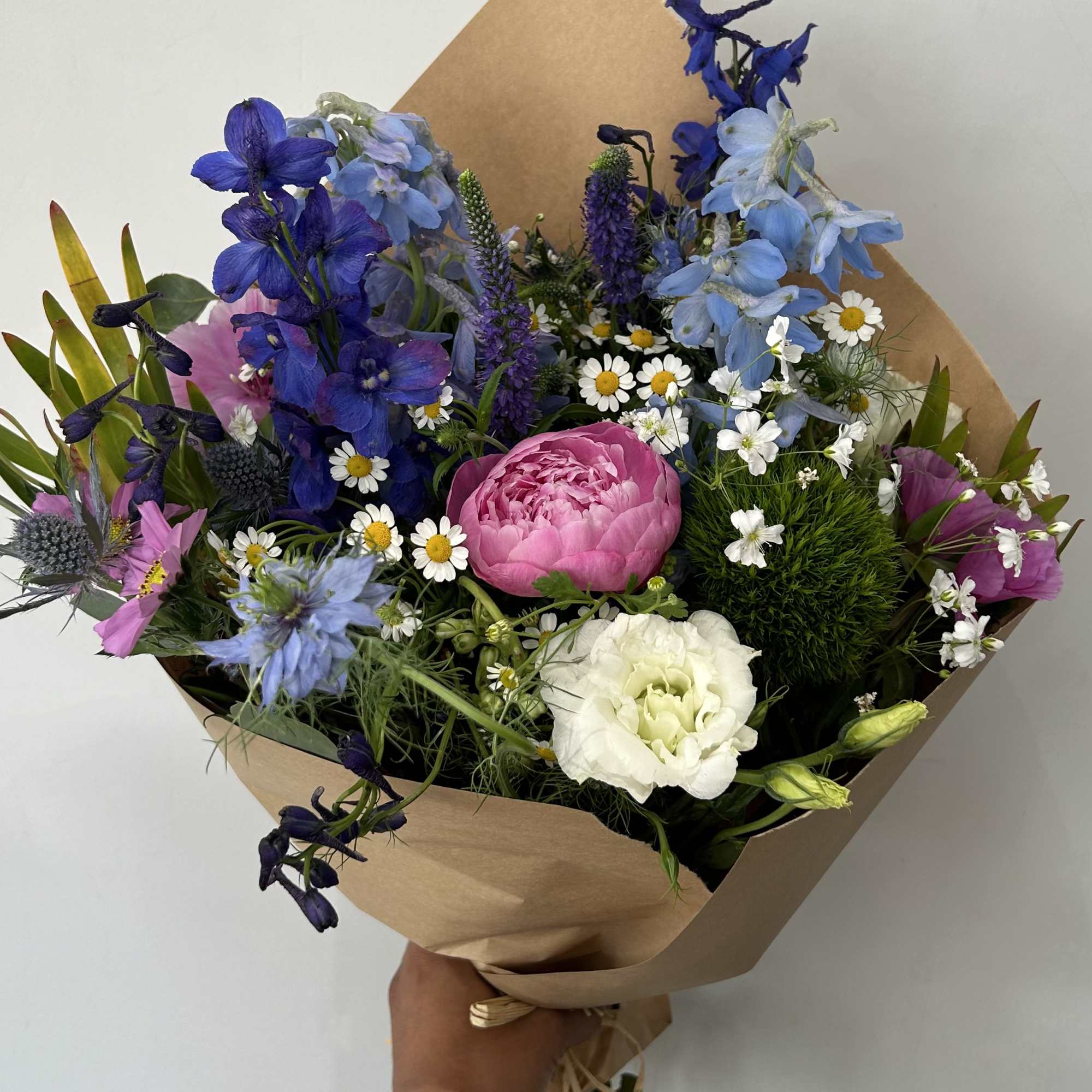 Seasonal wild flowers with a peony wrapped into a bouquet. 