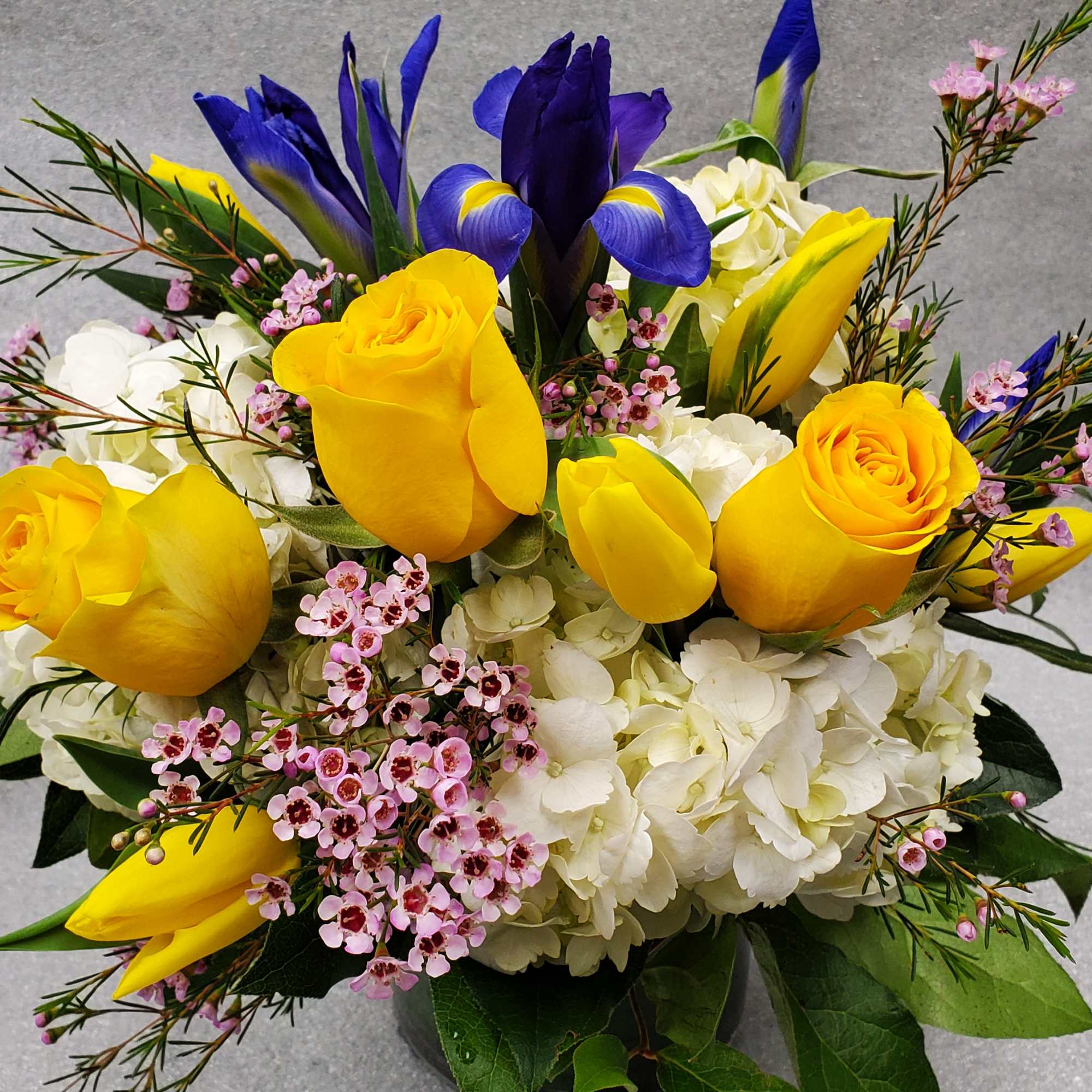 This design is in a lower clear vase and features, yellow roses