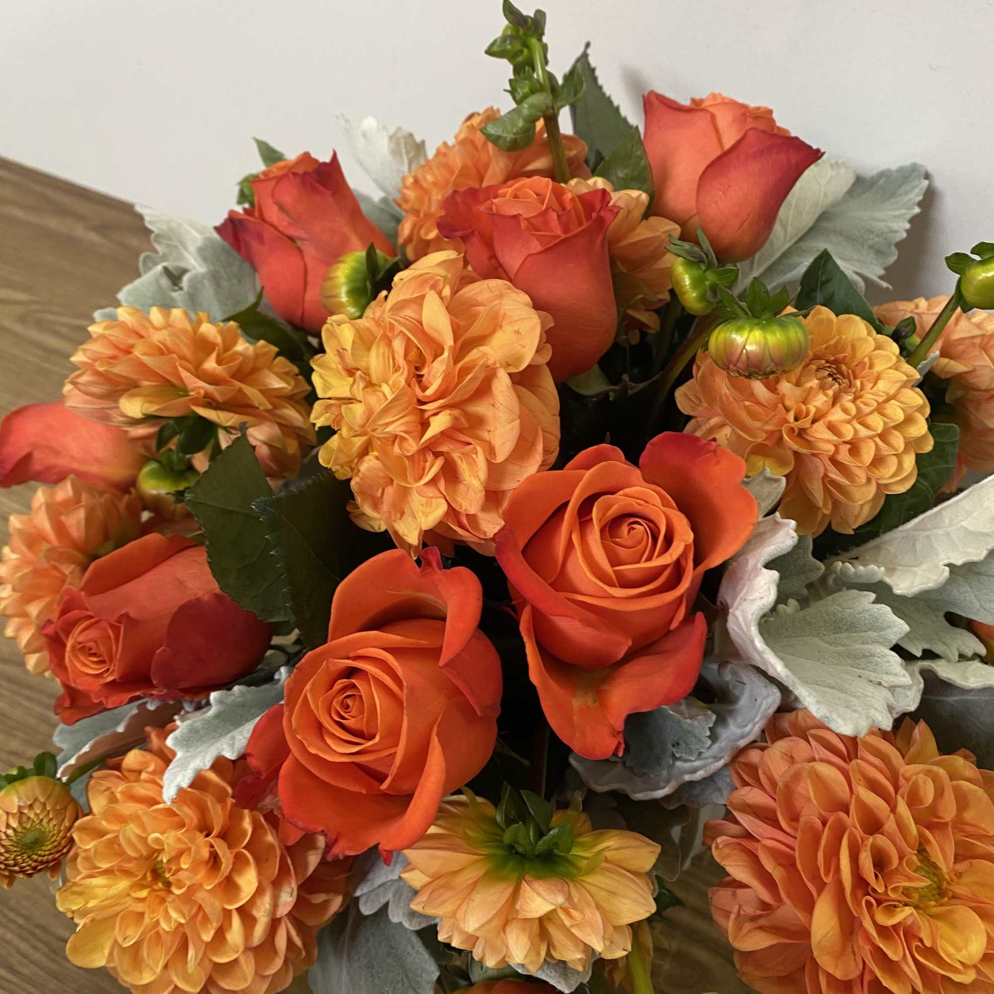 In a glass vase combinations of orange dollar and orange roses